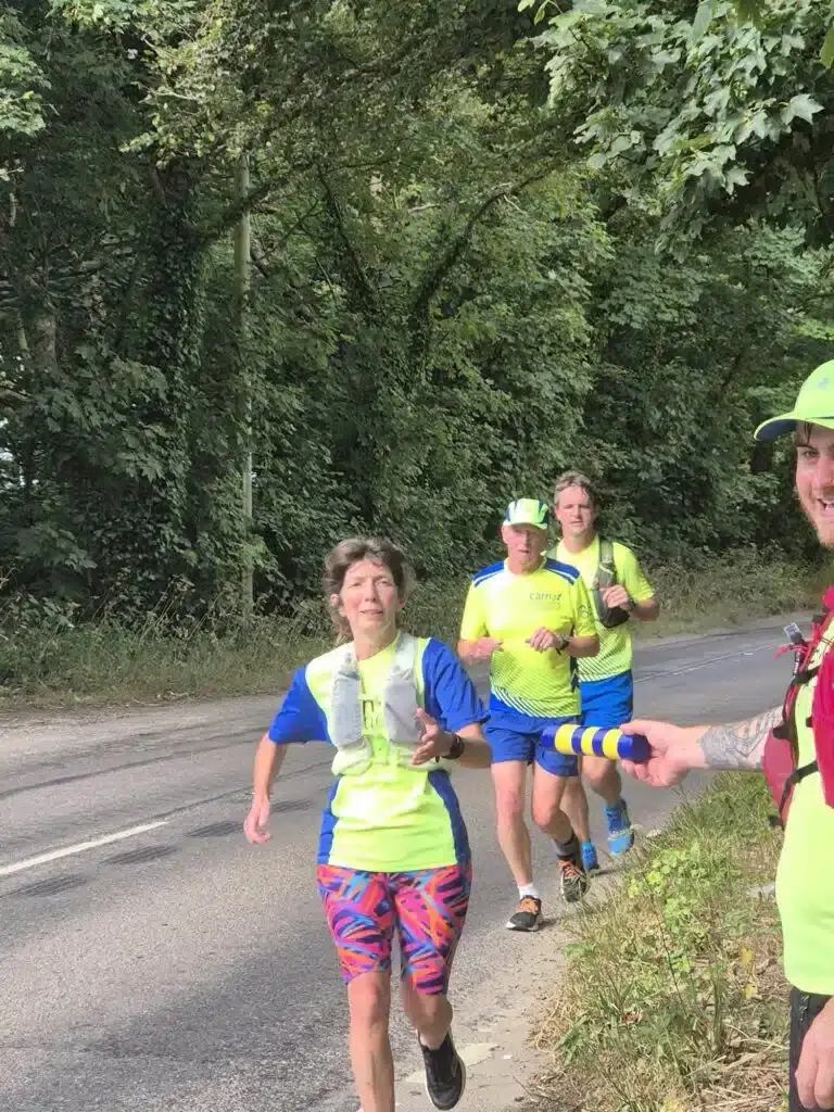 Carn Runners on a country road during a relay leg, one holding the blue and yellow baton