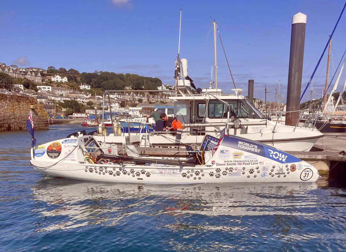 The rowing boat Row Aurora docked in Newlyn harbour on a sunny morning