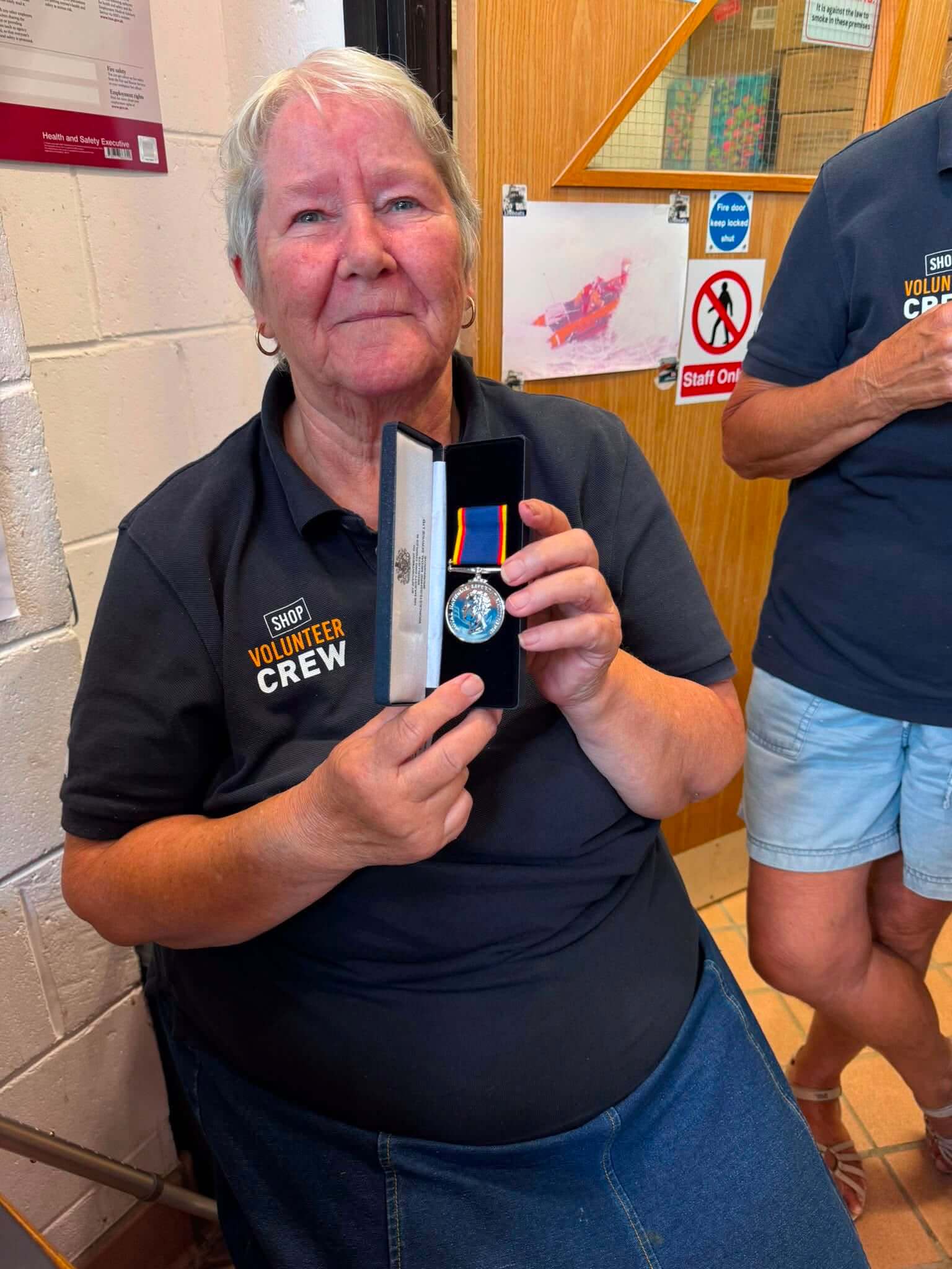 Janet Kearton holding her RNLI Long Service Medal in its presentation box at Newquay lifeboat station