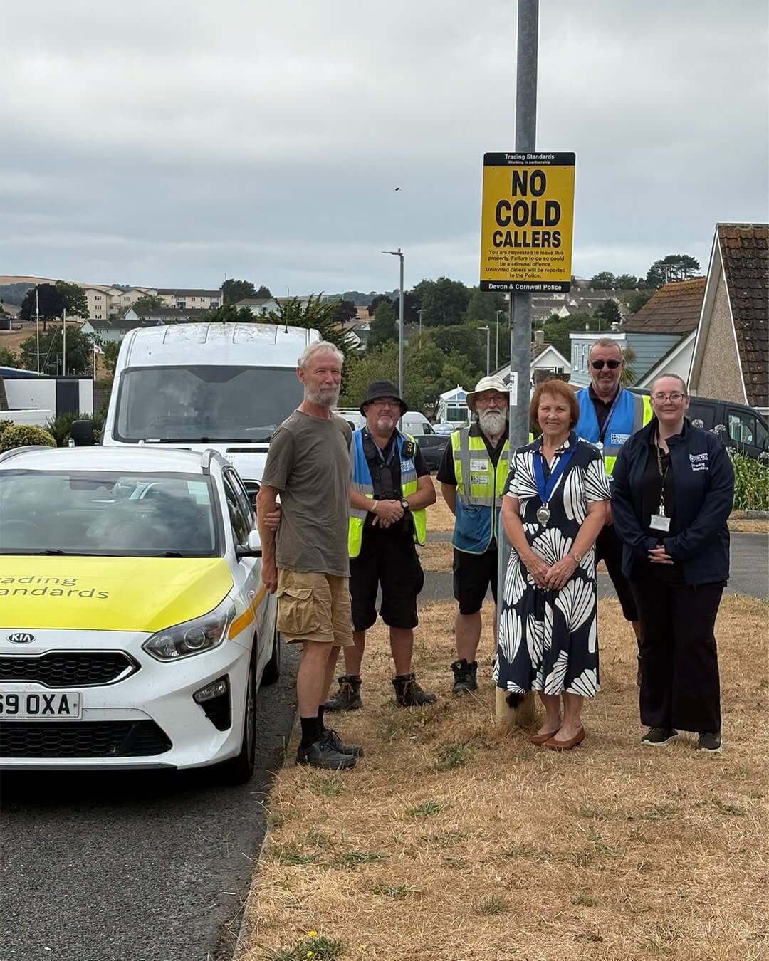 Residents, Trading Standards and community officers gather beside a new No Cold Callers sign