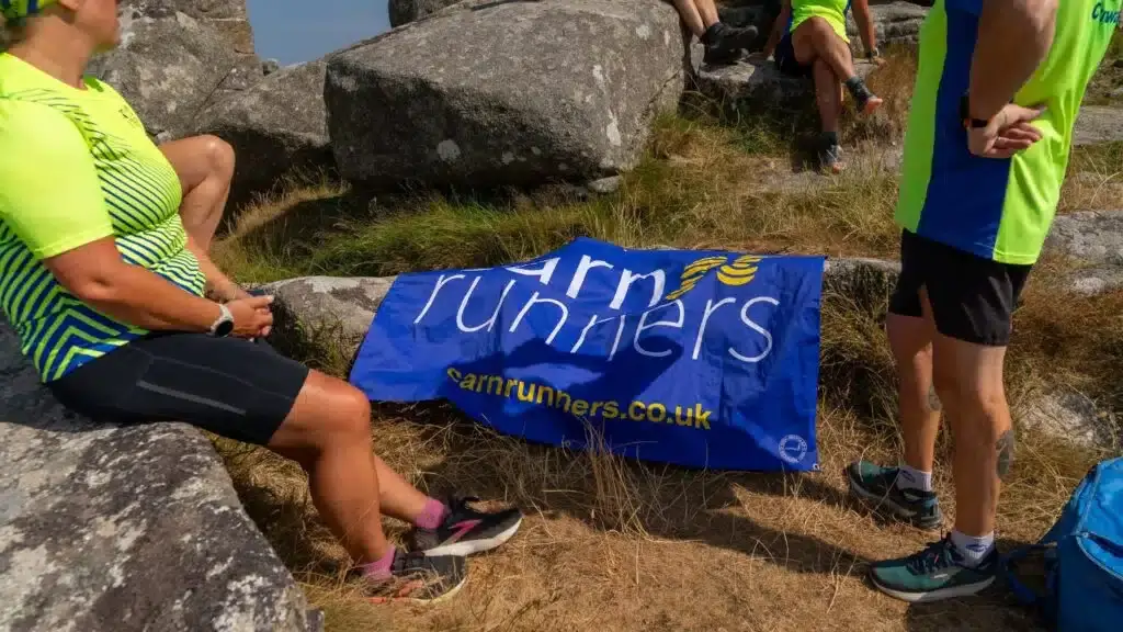The Carn Runners flag laid out on the grass on top of Carn Brea