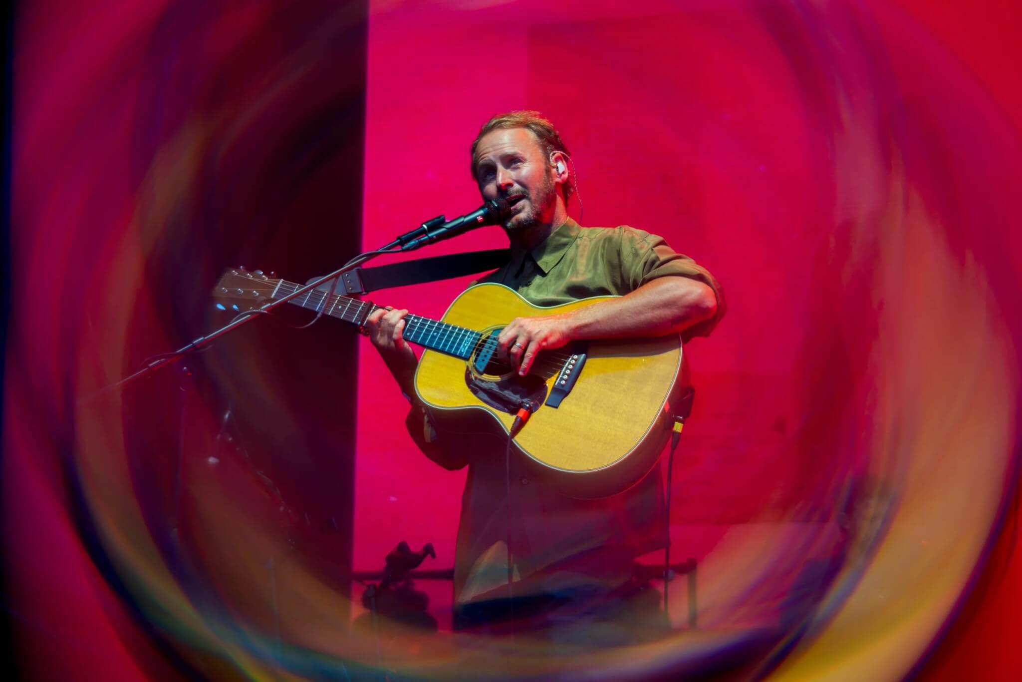Ben Howard playing acoustic guitar against a red backdrop at the Eden Sessions 2026 (photo Rob Donald)