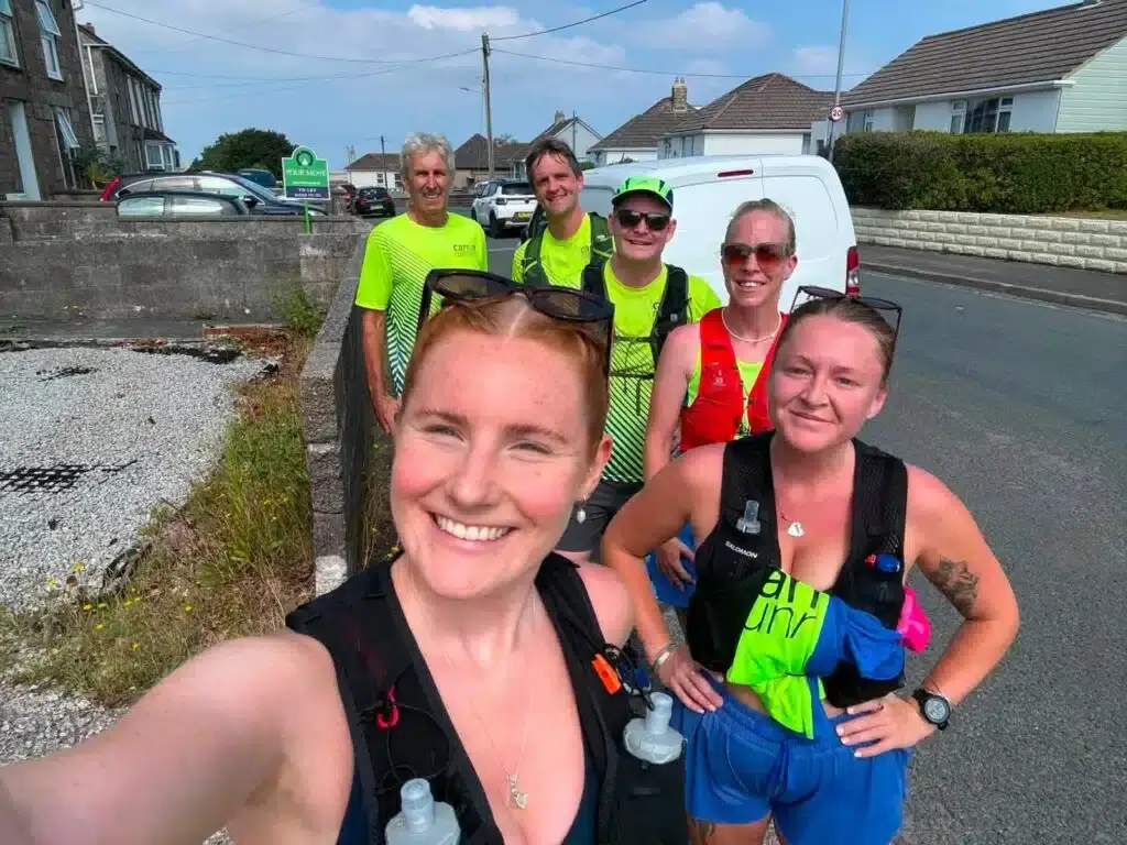 A group of Carn Runners smiling for a selfie on a street during the relay