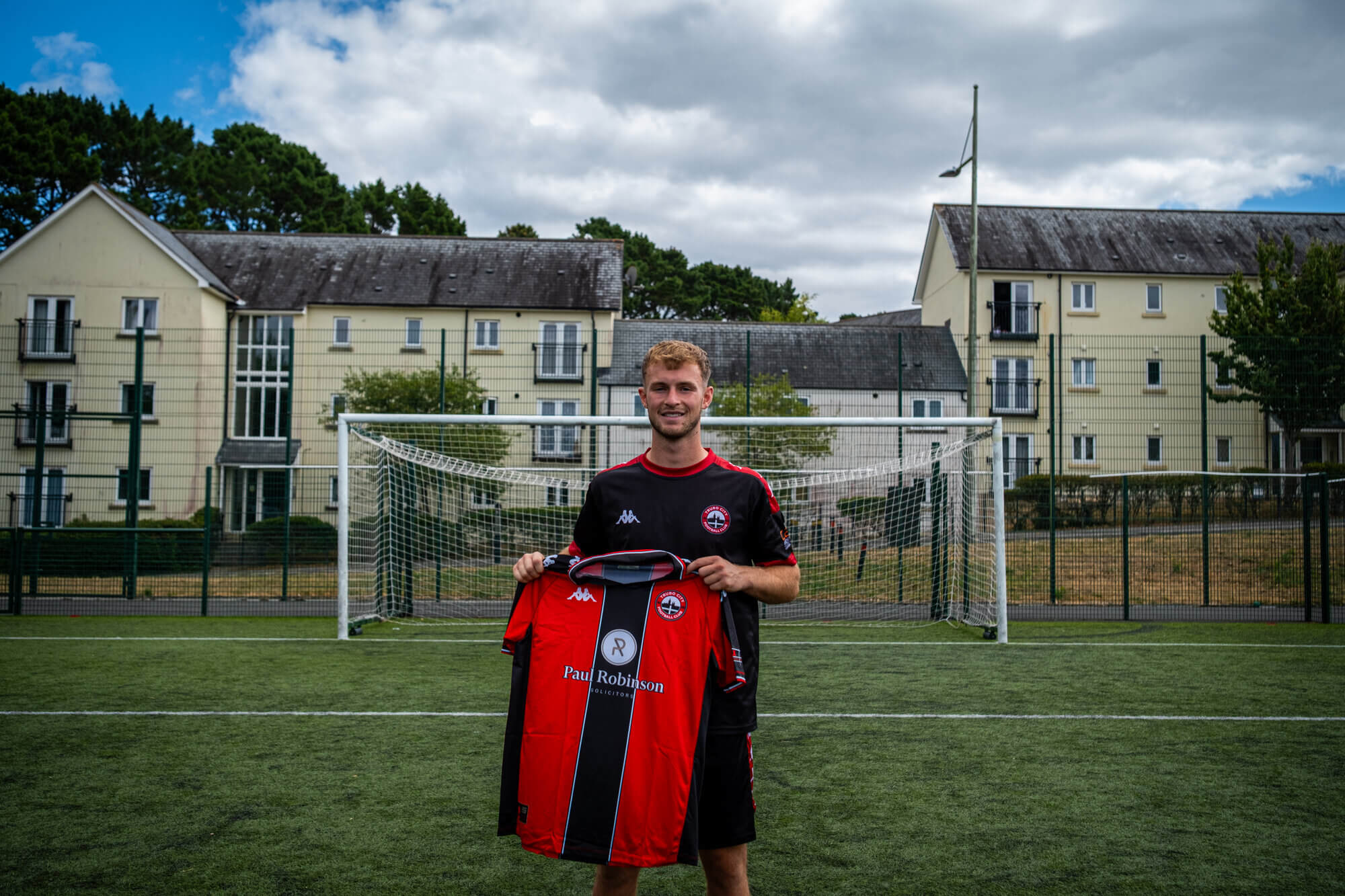 Max Kinsey holding up the Truro City home shirt on the pitch
