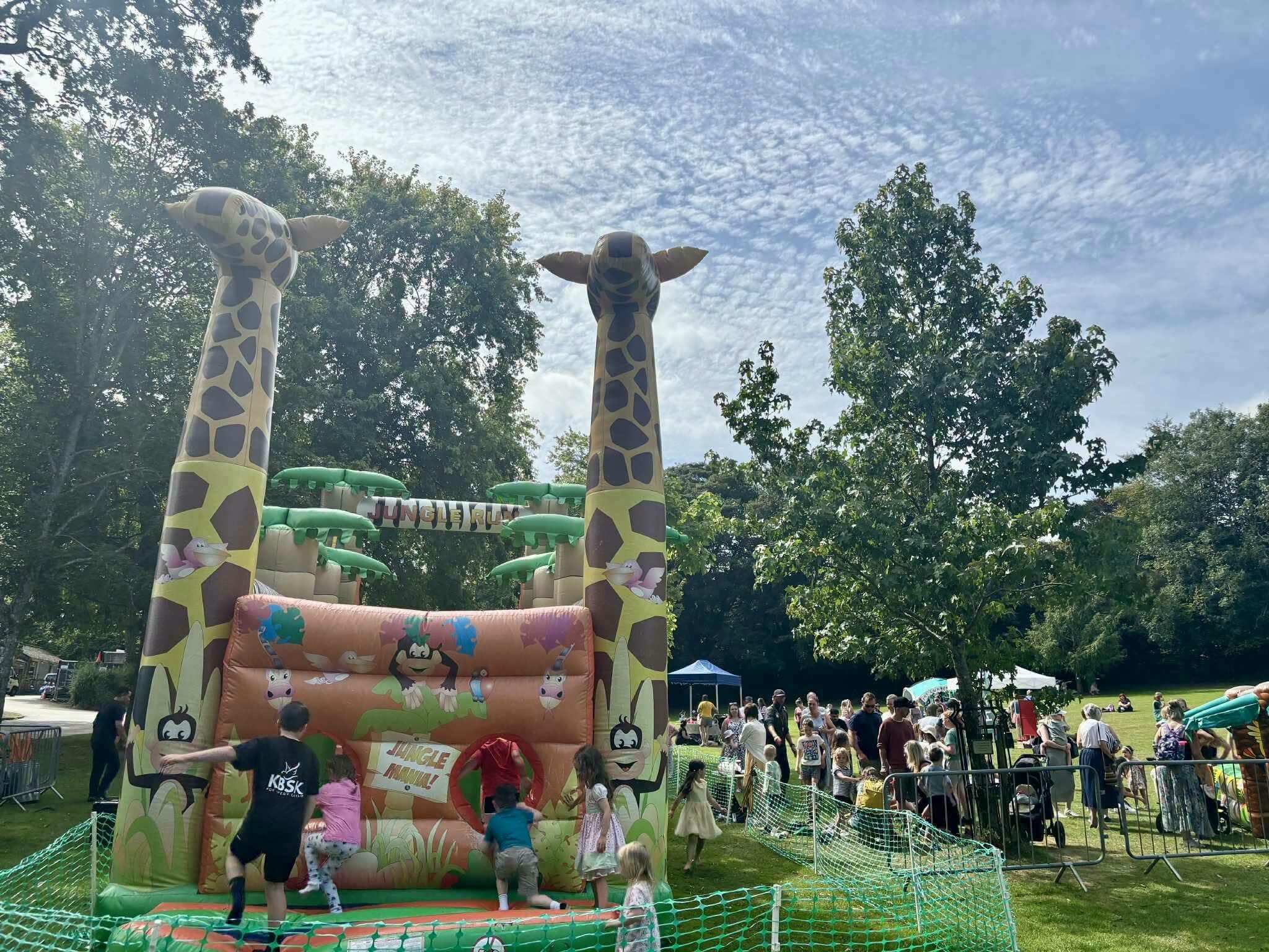 Giraffe-themed Jungle Run inflatable and families at an event in Priory Park, Bodmin