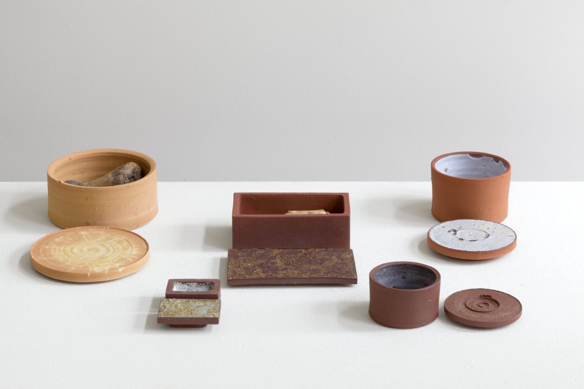 A group of red and terracotta ceramic ossuary vessels and lids by Julian Stair
