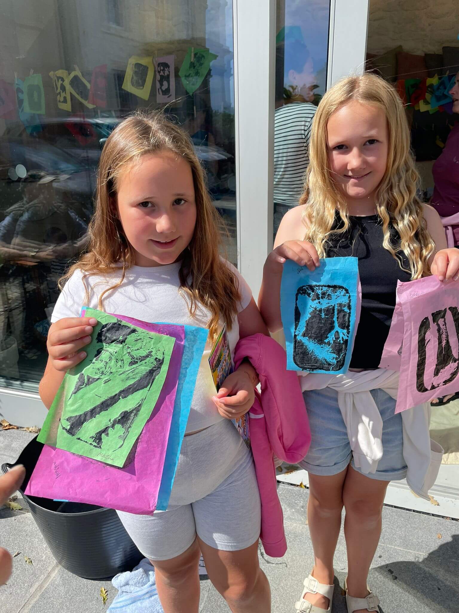 Two children hold up prints they made at a Gardeners' House workshop