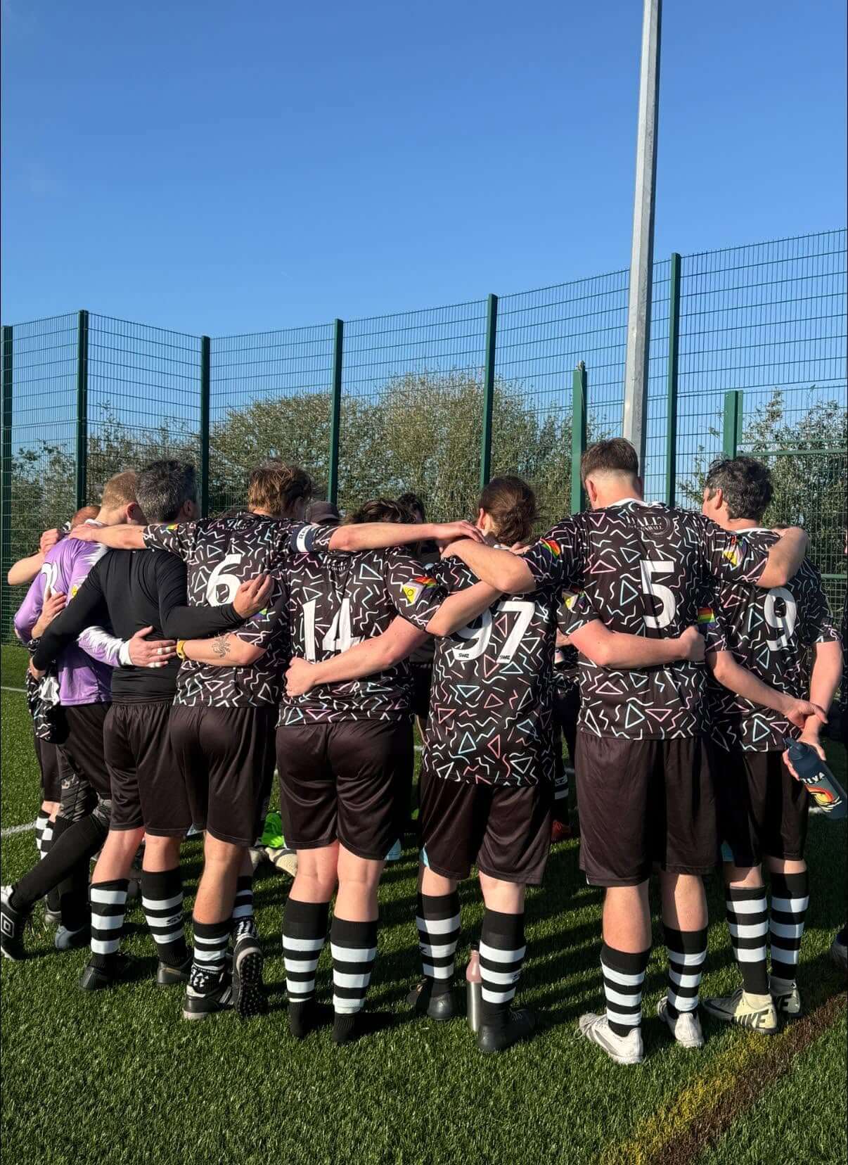 Stargazy FC players in a team huddle before kick-off under blue skies
