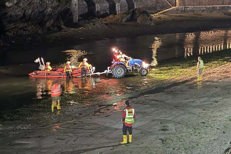 RNLI Looe D Class lifeboat recovered by tractor at low tide at night