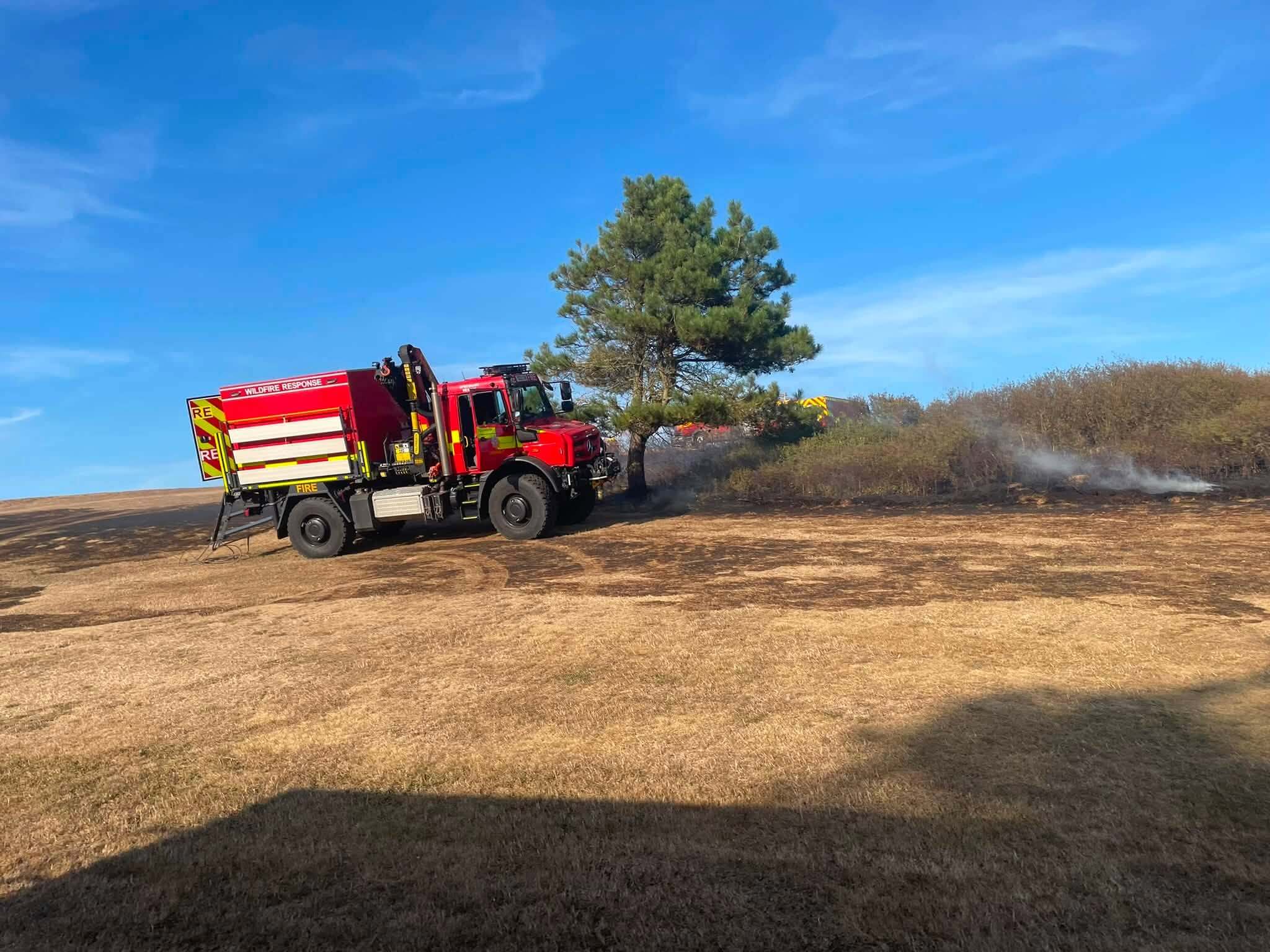 Cornwall Fire and Rescue wildfire response engine on burnt open ground with smoke