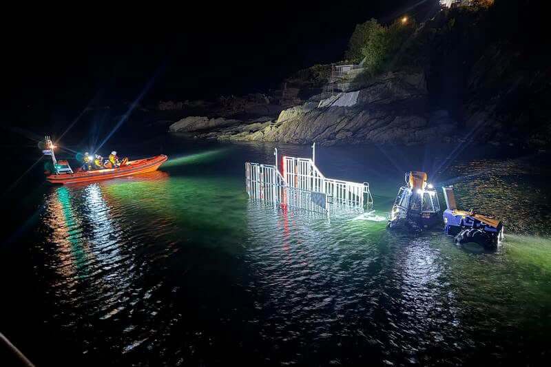 RNLI Looe lifeboats being recovered at night beside the rocks