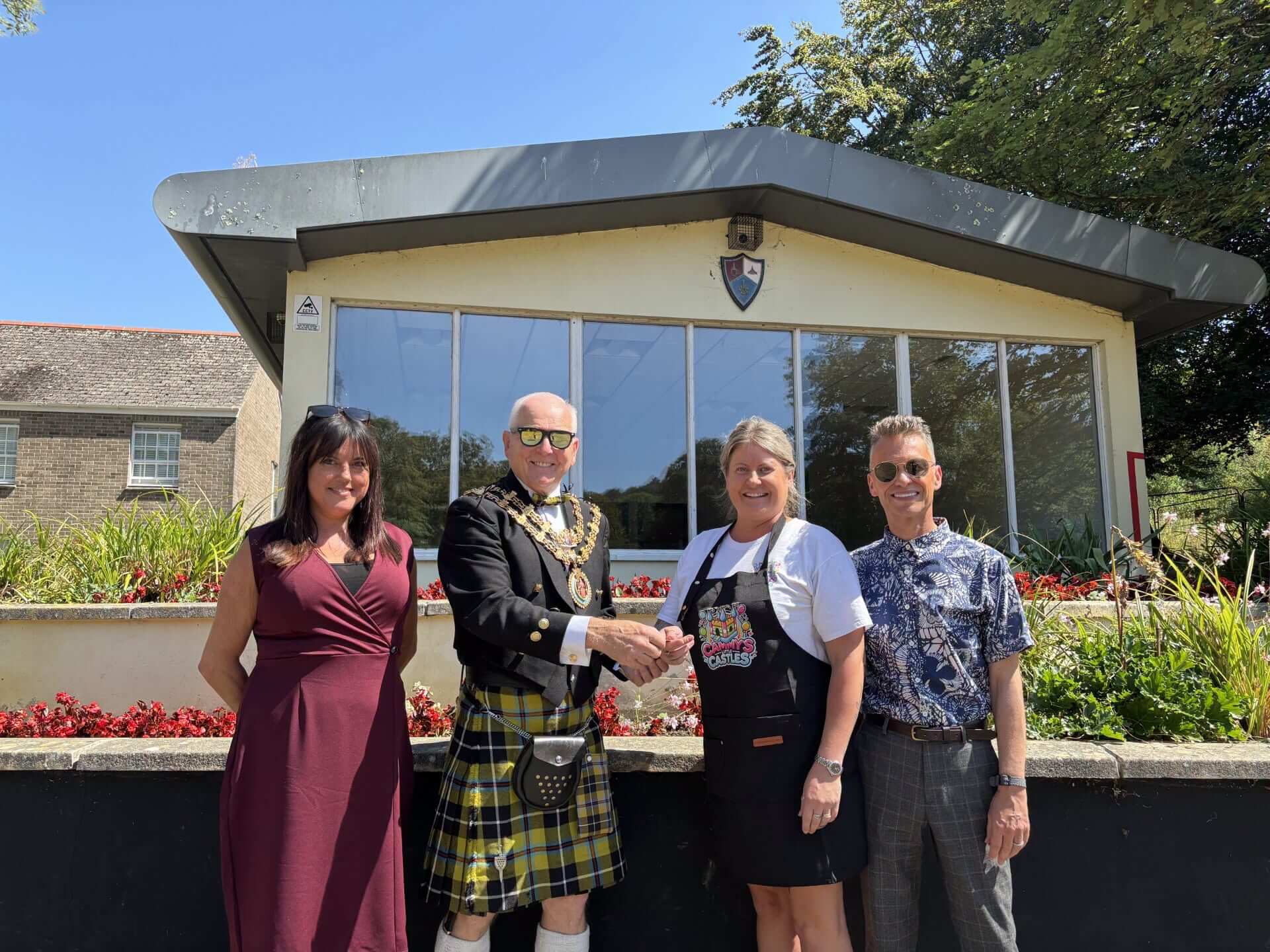 Four people stand outside Narisa Hall in Priory Park, Bodmin, as the keys are handed over