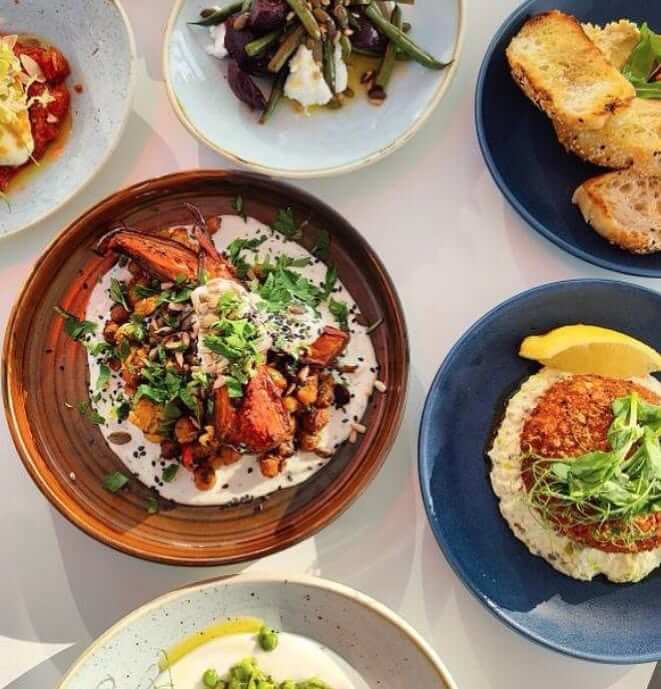 A spread of Mediterranean small plates and salads on a table