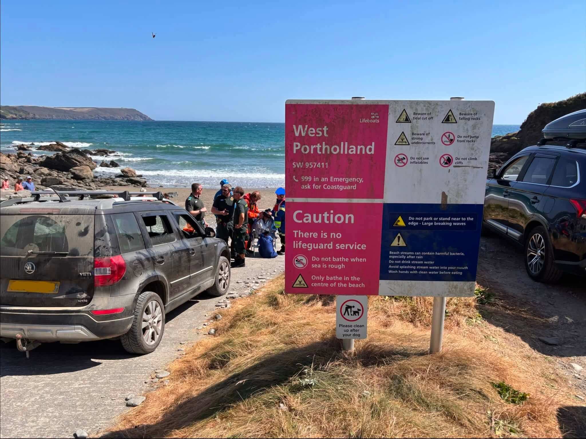 Emergency crews on the beach beside the West Portholland safety sign
