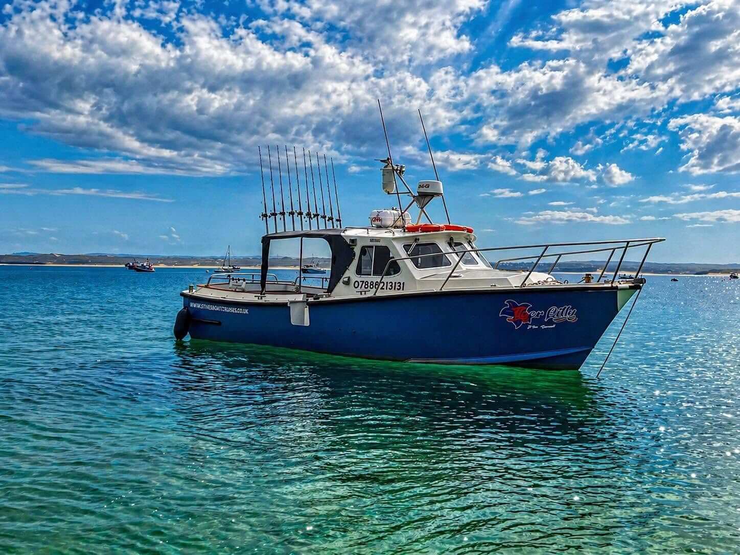 The Tiger Lily boat moored on bright turquoise water off St Ives