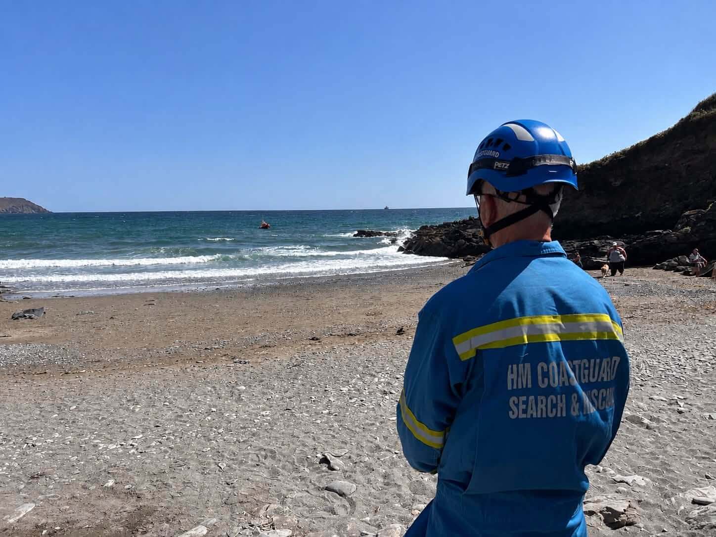 HM Coastguard search and rescue officer watching the sea from the beach at West Portholland