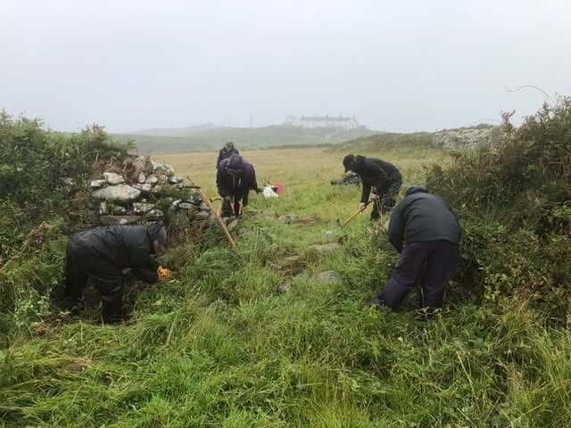Volunteers clearing and conserving a Cornish heritage site in the rain