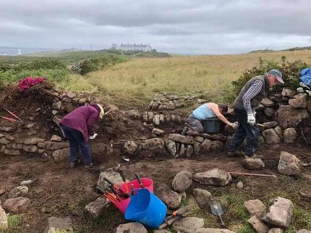 Volunteer team working together on a heritage wall restoration in Cornwall