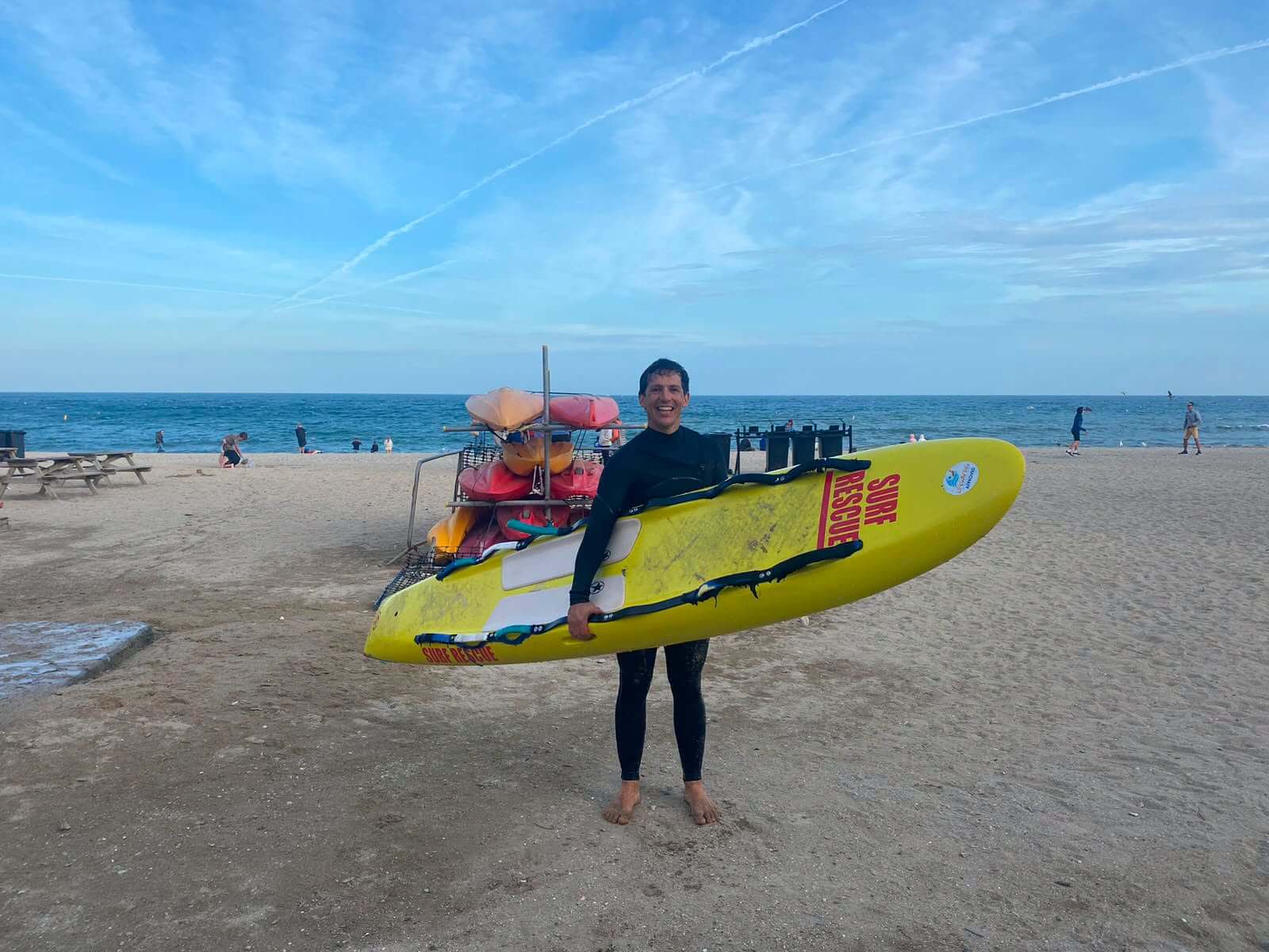 A Gyllyngvase Surf Life Saving Club volunteer on the beach with a surf rescue board