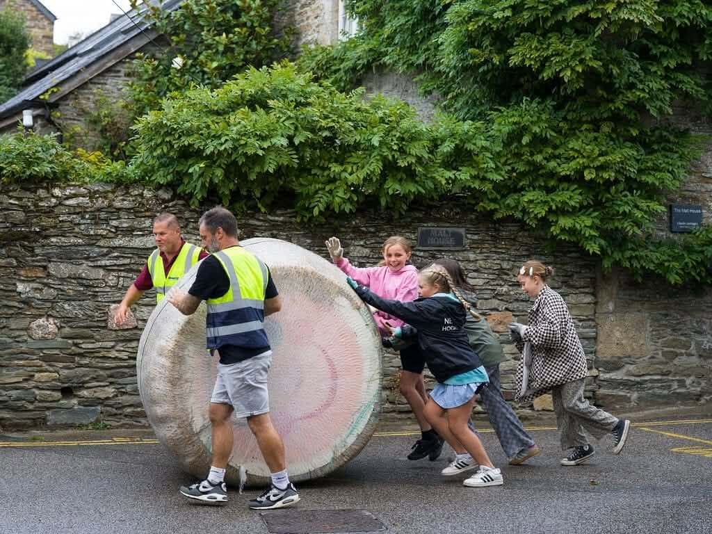 Volunteers and children push the giant bale through Crantock