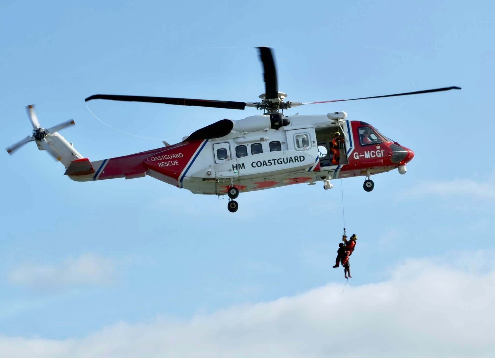 HM Coastguard helicopter crew winch two people up from the water off Marazion