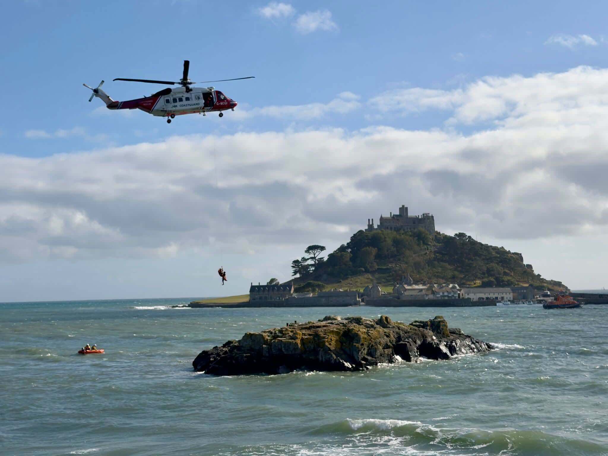 HM Coastguard helicopter Rescue 924 winches a person to safety near St Michael's Mount, Marazion