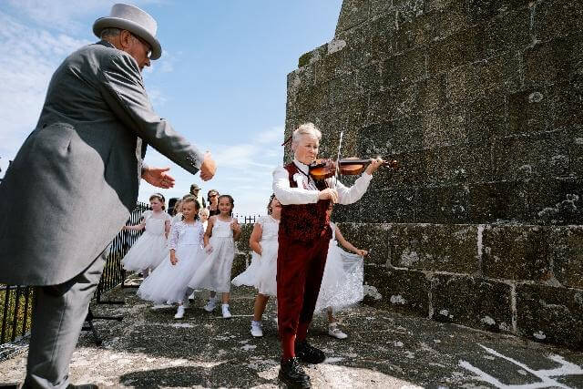 A man in a grey top hat greets the fiddler as the maids dance at the Knill Steeple