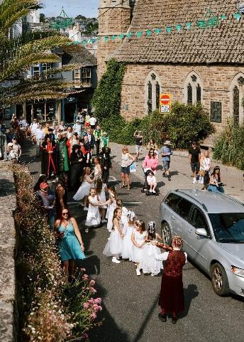 The John Knill procession moves along a St Ives street past the church and bunting