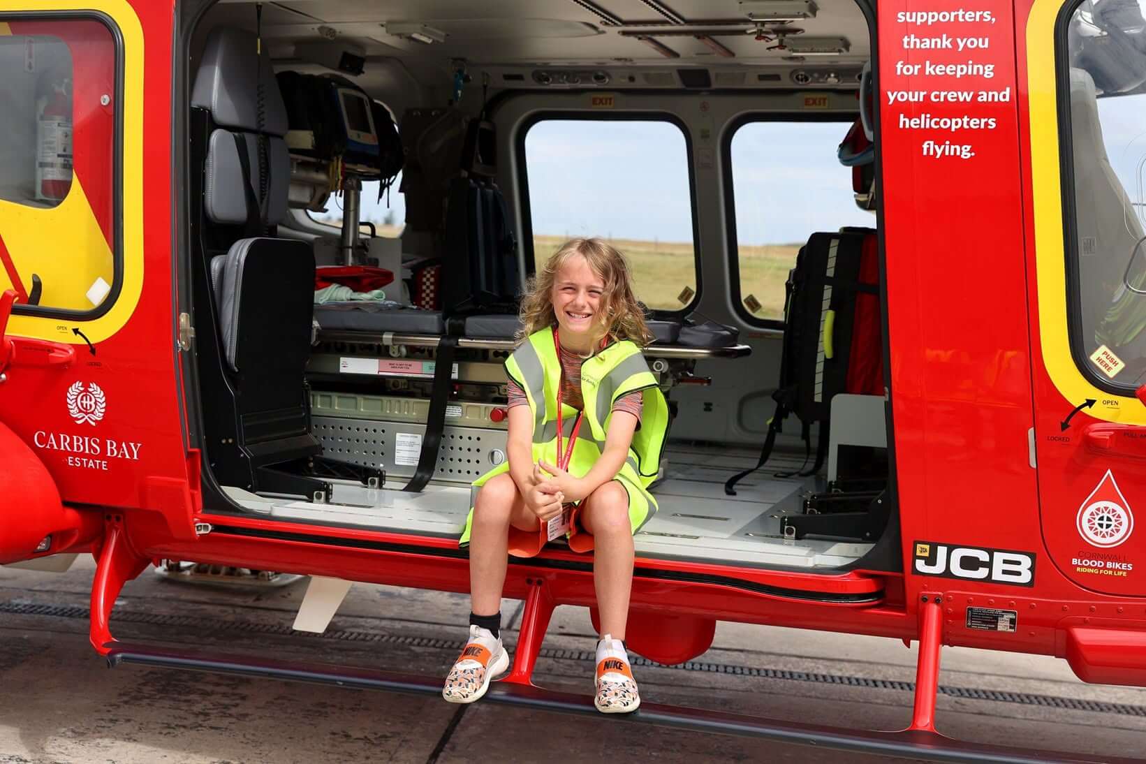 Freddie sitting smiling in the doorway of the Cornwall Air Ambulance helicopter