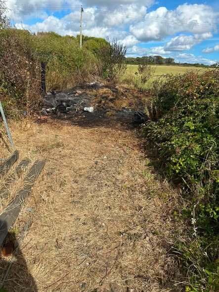 Blackened ground and burnt debris along a field-edge path after a fire near Bude