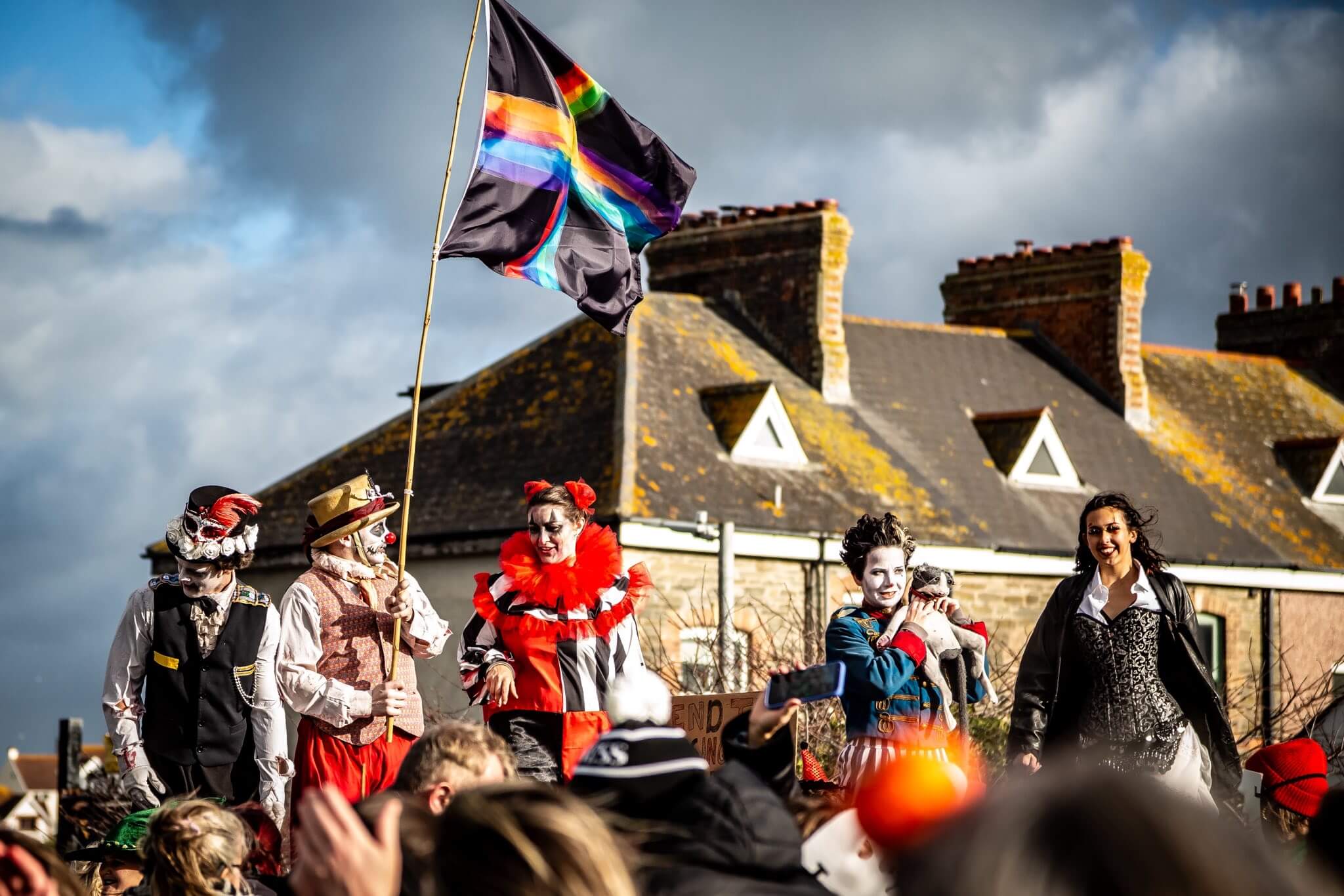 Painted performers carry the Spooky Newquay flag past Newquay's rooftops