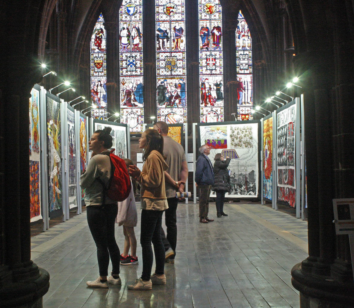 Families looking at rows of embroidered panels in the cathedral nave