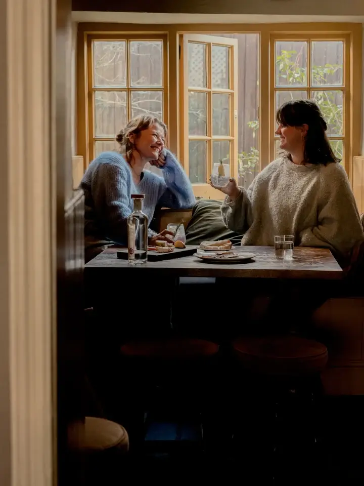 Loveday Distillery founders Chloe and Daisy sharing drinks by a window