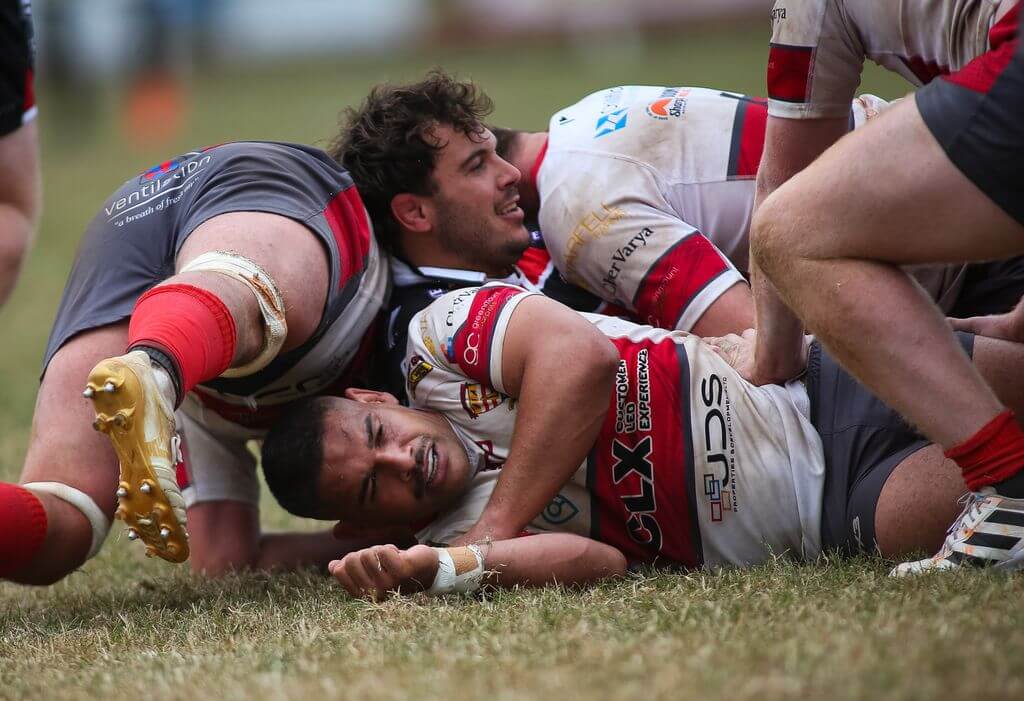 Camborne and Cornish Pirates players contest the ball on the ground at The Rec