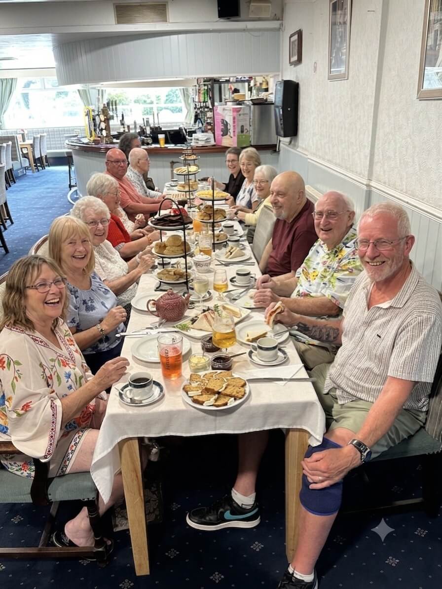 Oddfellows members gathered around a long table for afternoon tea with tiered cake stands at Camborne Conservative Club