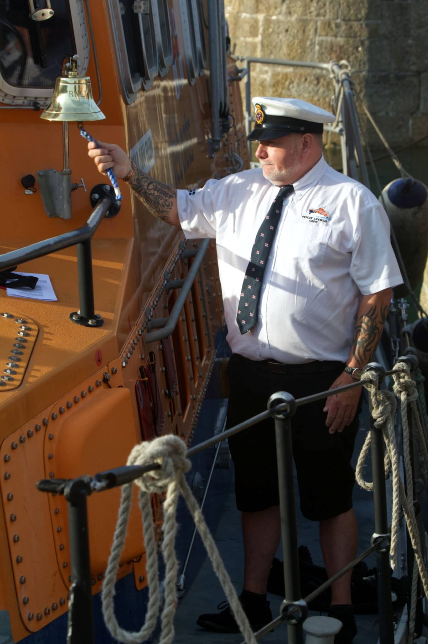 A Penlee RNLI volunteer rings the lifeboat's bell during the service