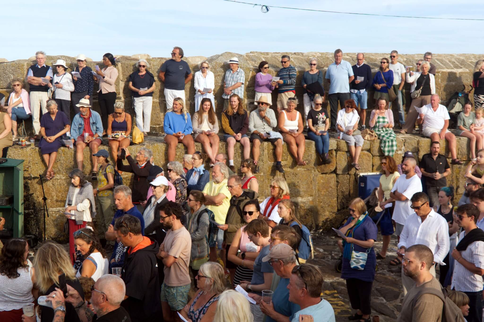 Crowd standing on the harbour wall at Mousehole for the RNLI blessing service