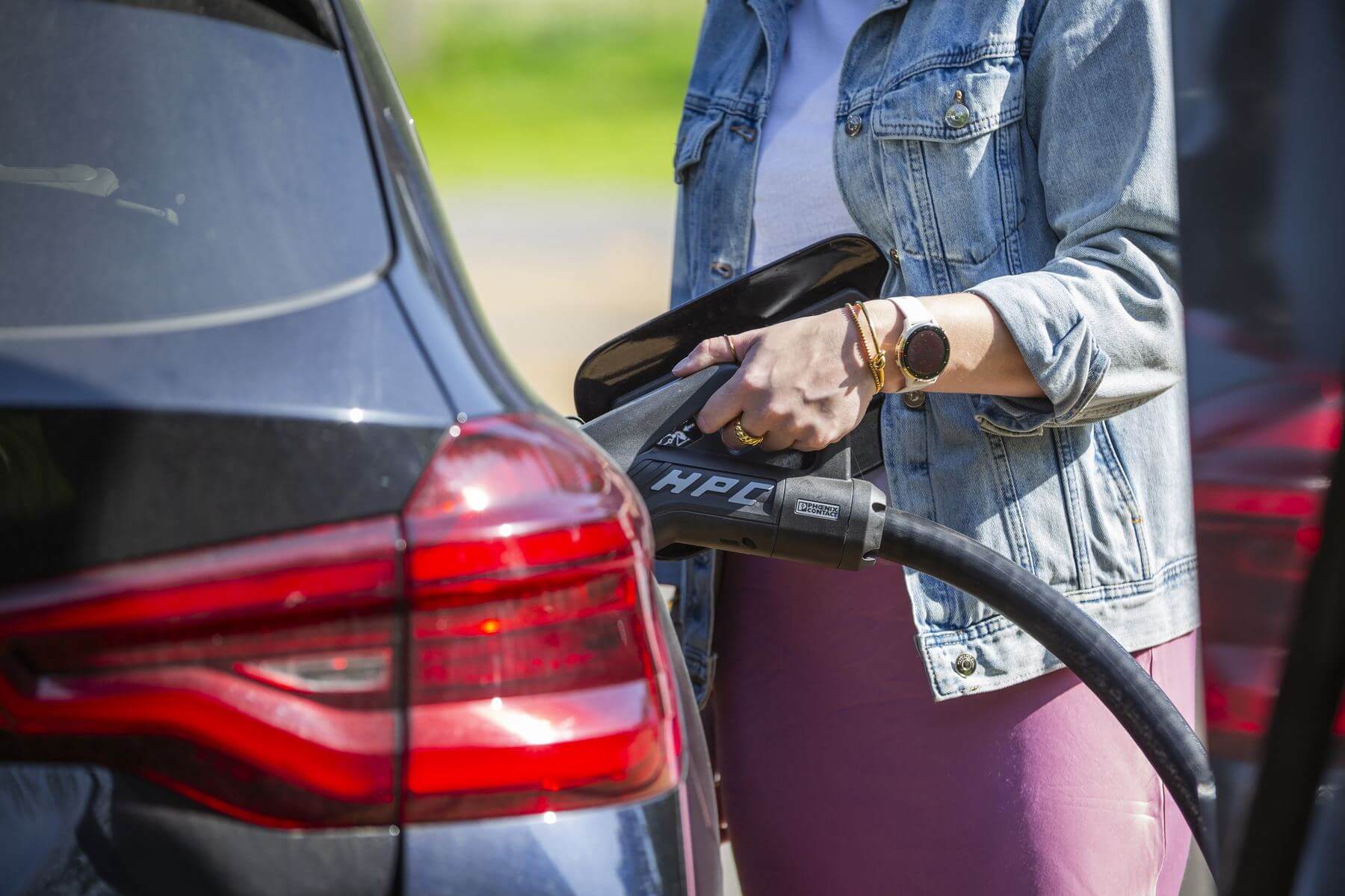 A driver plugging in an electric car to charge