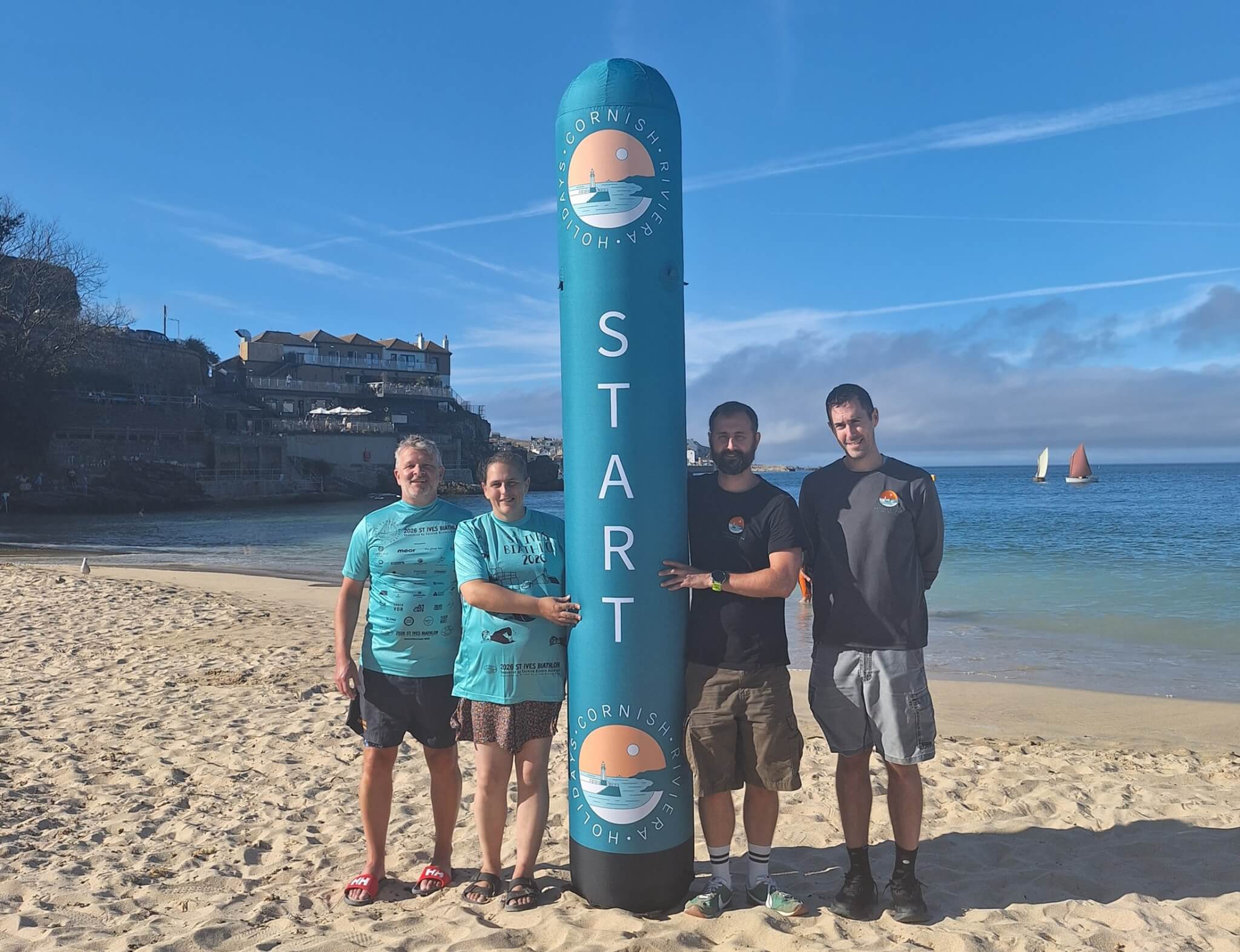 Four St Ives Surf Life Saving Club members beside the inflatable Biathlon start marker on the beach at St Ives