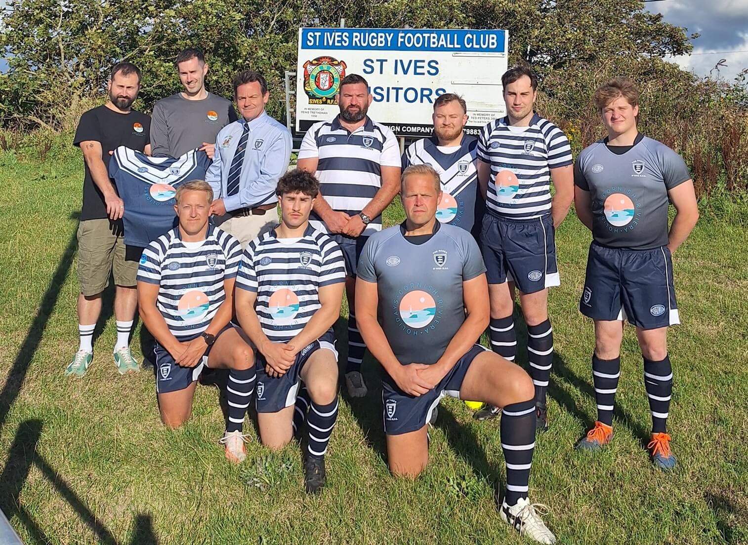 St Ives RFC chair, director of rugby, Cornish Riviera Holidays directors and players in front of the St Ives RFC sign