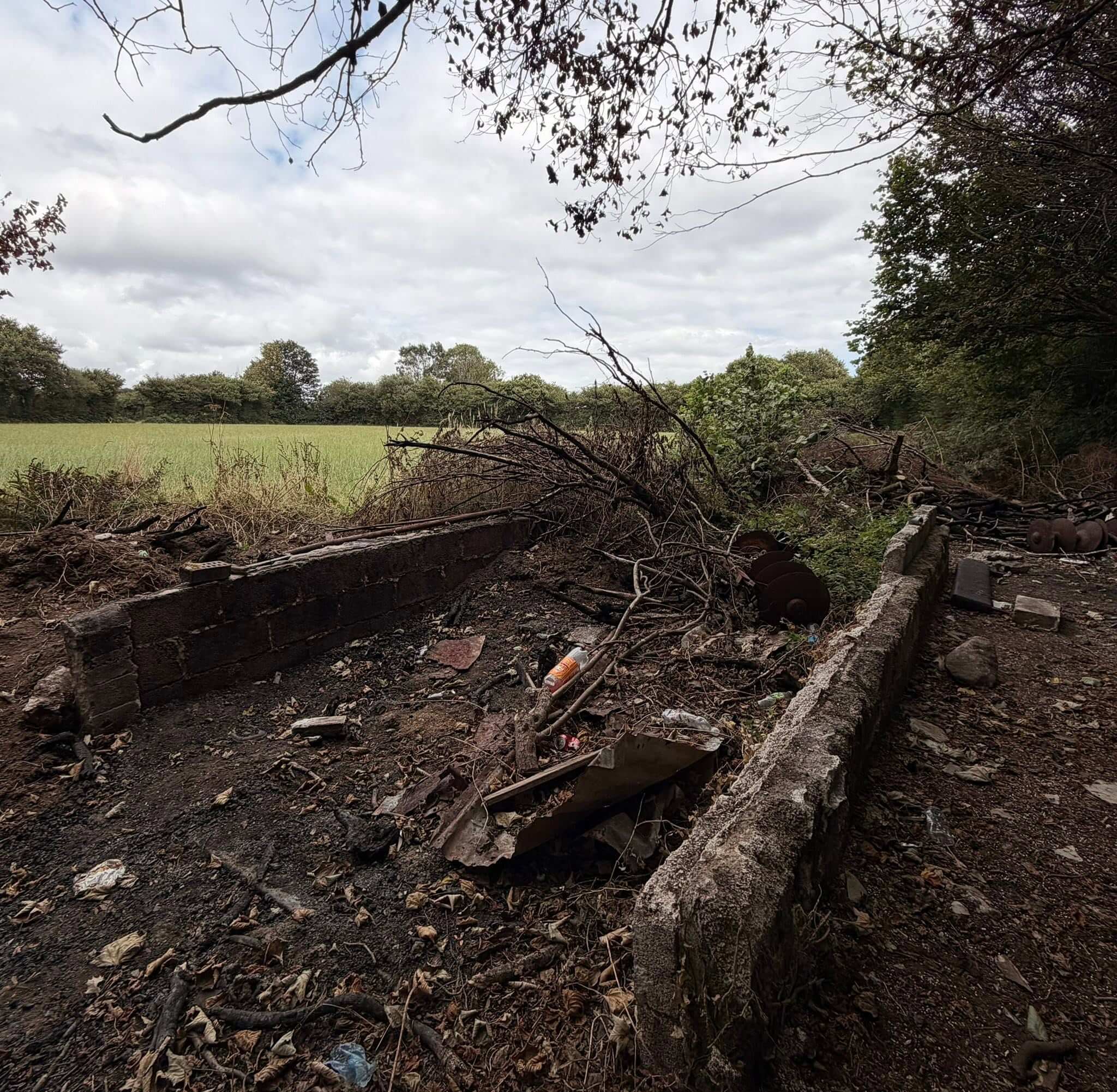 Burnt debris and old brick walls beside a field on the land behind Callington Tesco