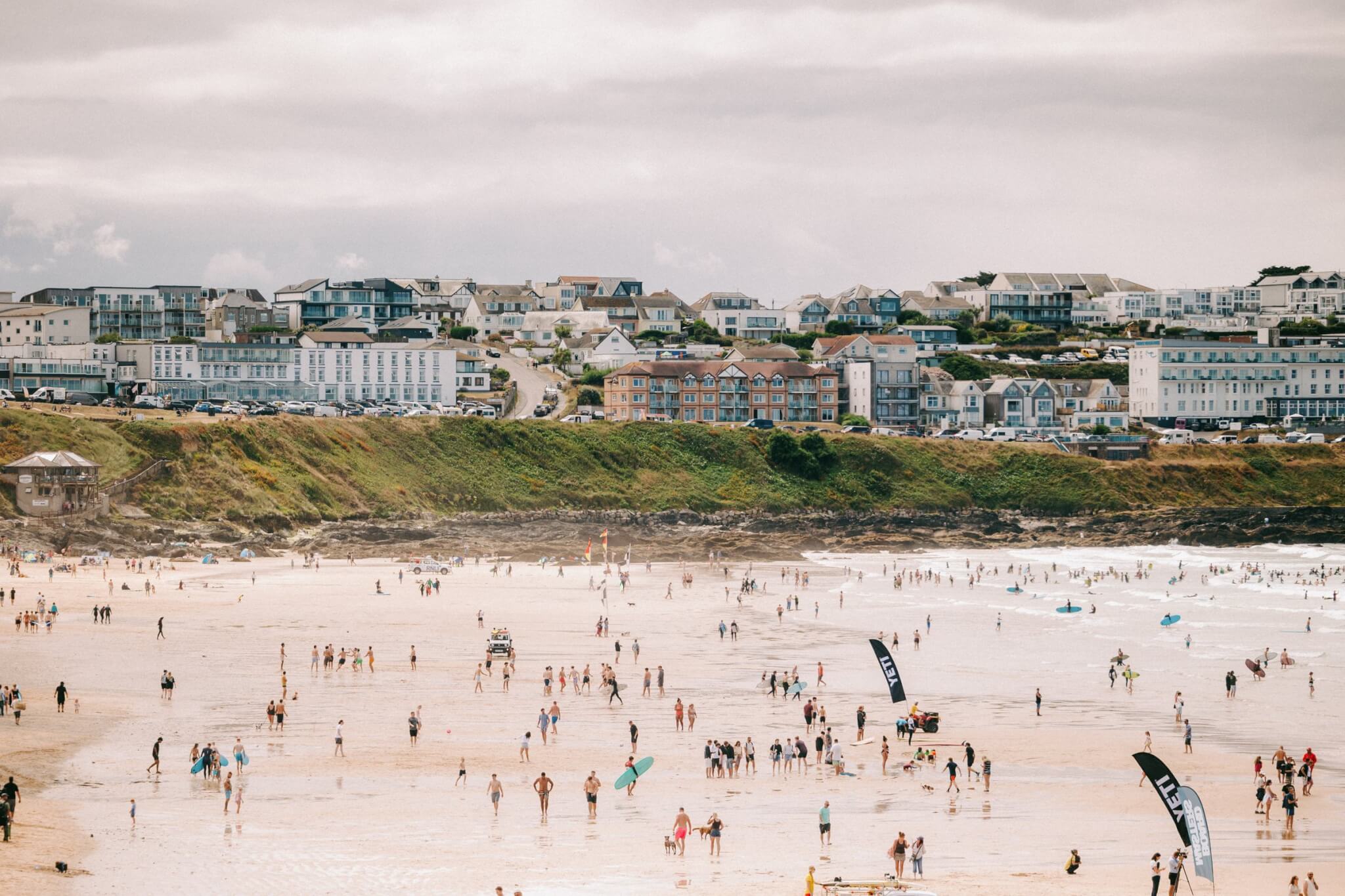 Crowds pack Fistral Beach in Newquay for the Boardmasters Open, with YETI flags on the sand and surfers in the water