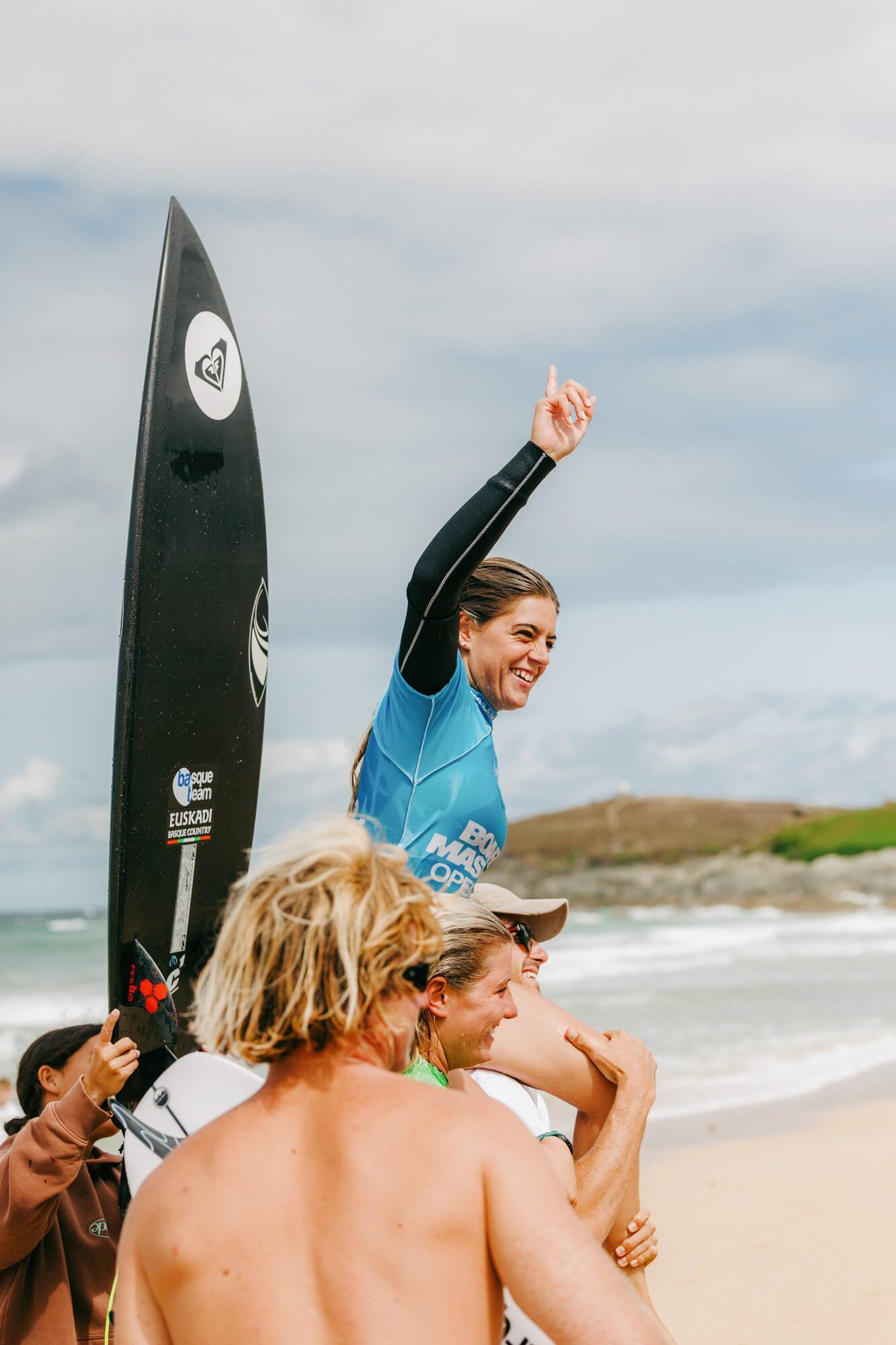 Women's champion Janire Gonzalez Etxabarri lifted on shoulders on the beach, pointing to the sky in celebration
