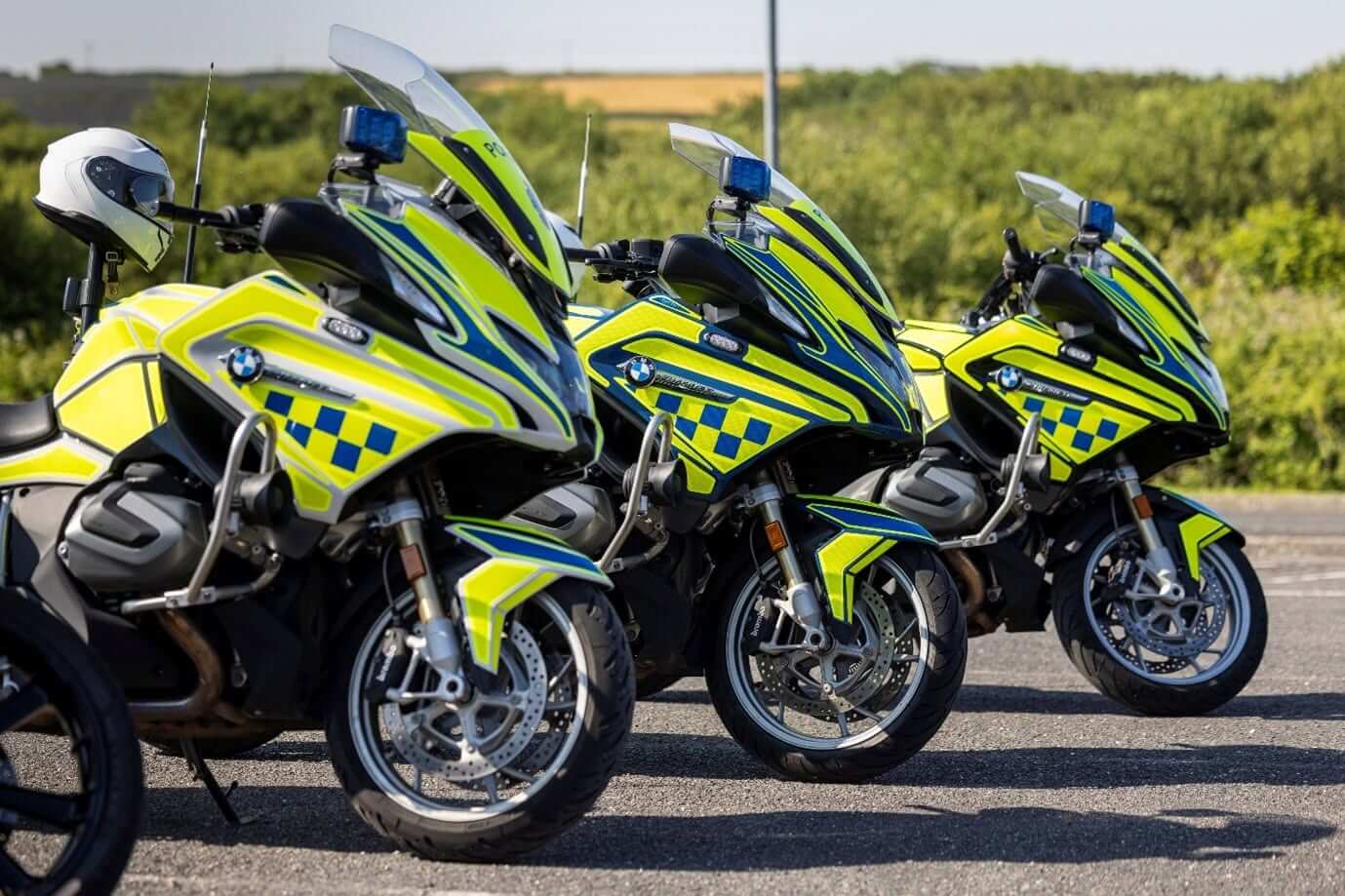 Three Devon and Cornwall Police BMW motorcycles in hi-vis livery parked in a row