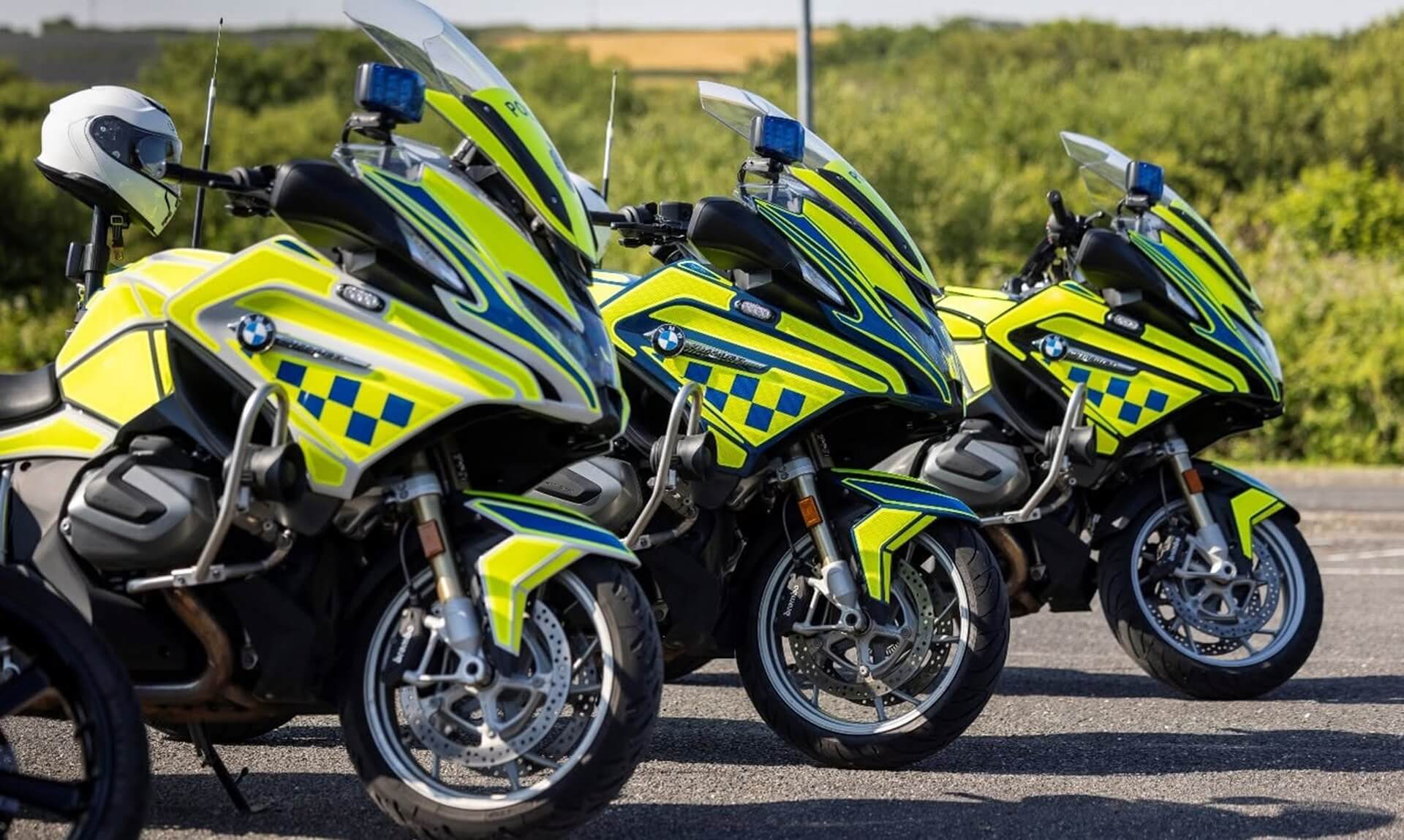 Three Devon and Cornwall Police BMW motorcycles in hi-vis livery parked in a row