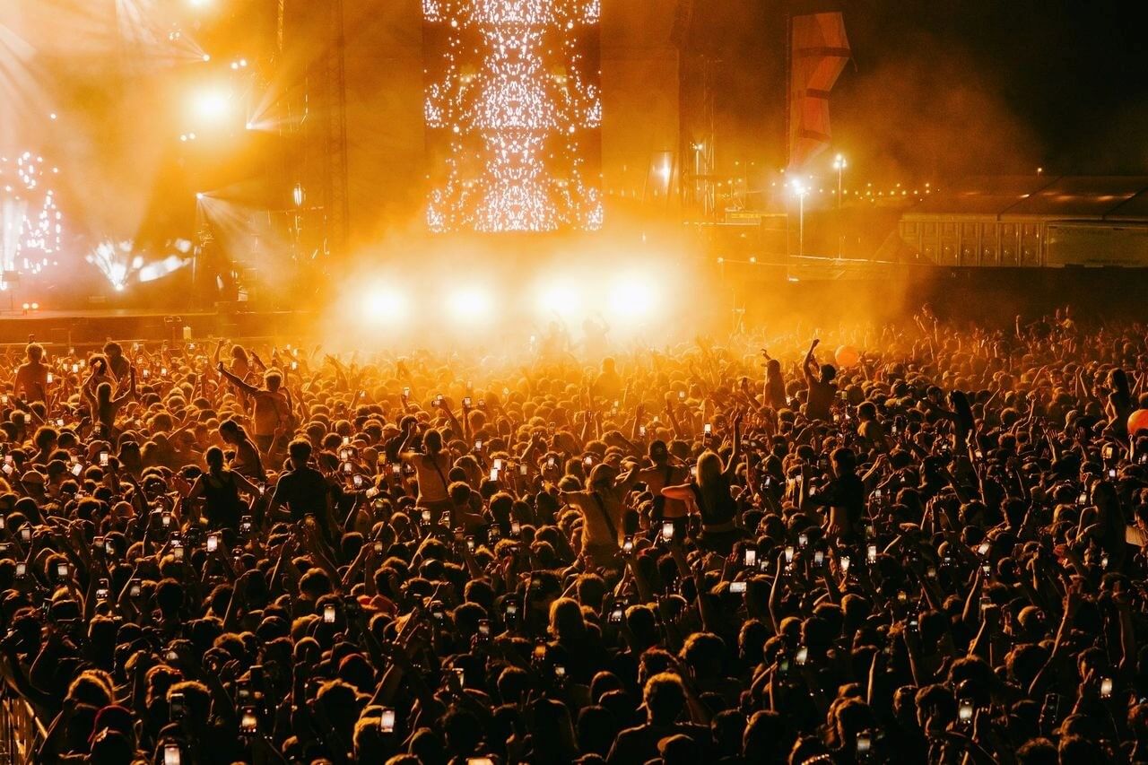 Boardmasters festival crowd at night under orange stage lights at Watergate Bay, Newquay
