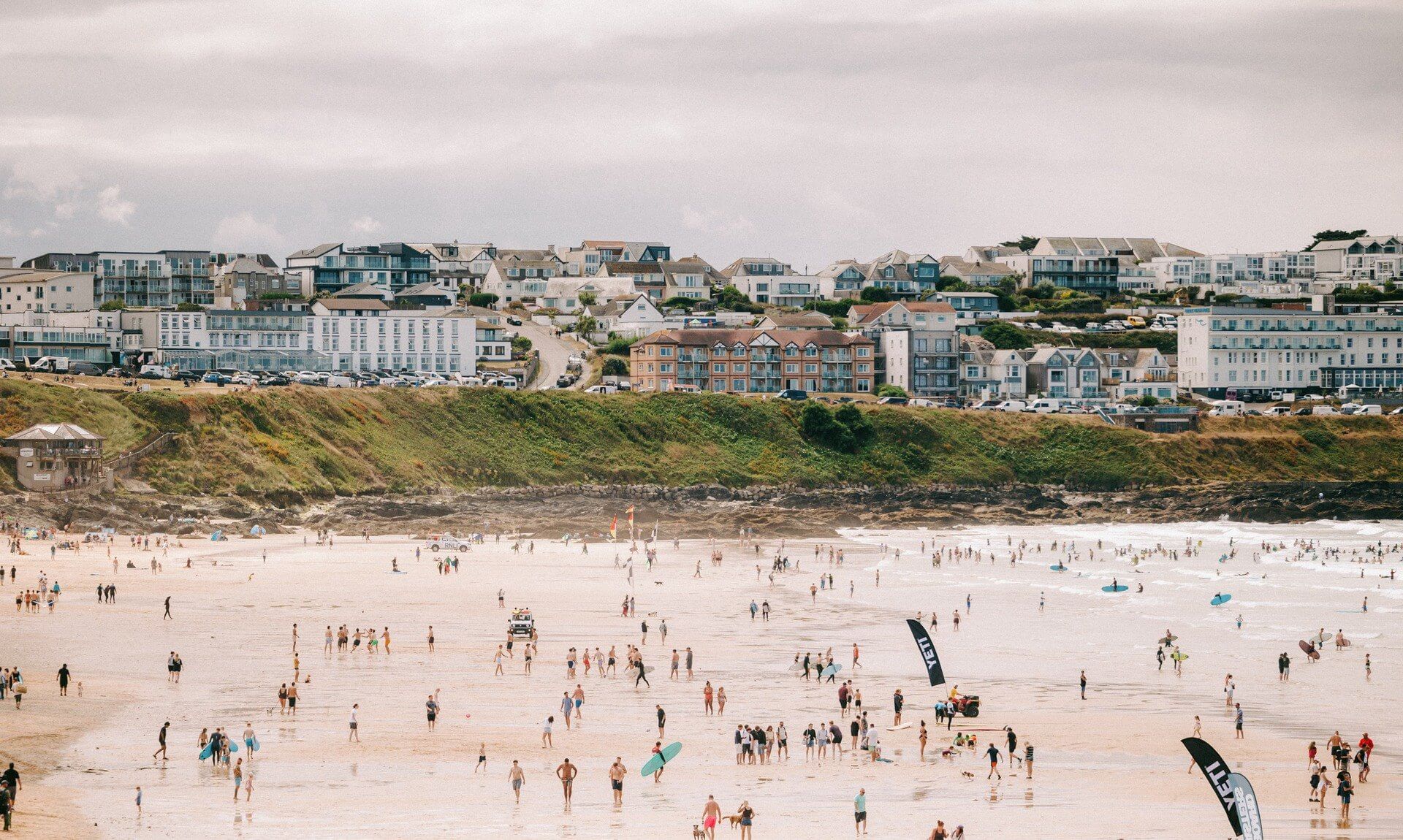 Crowds pack Fistral Beach in Newquay for the Boardmasters Open, with YETI flags on the sand and surfers in the water