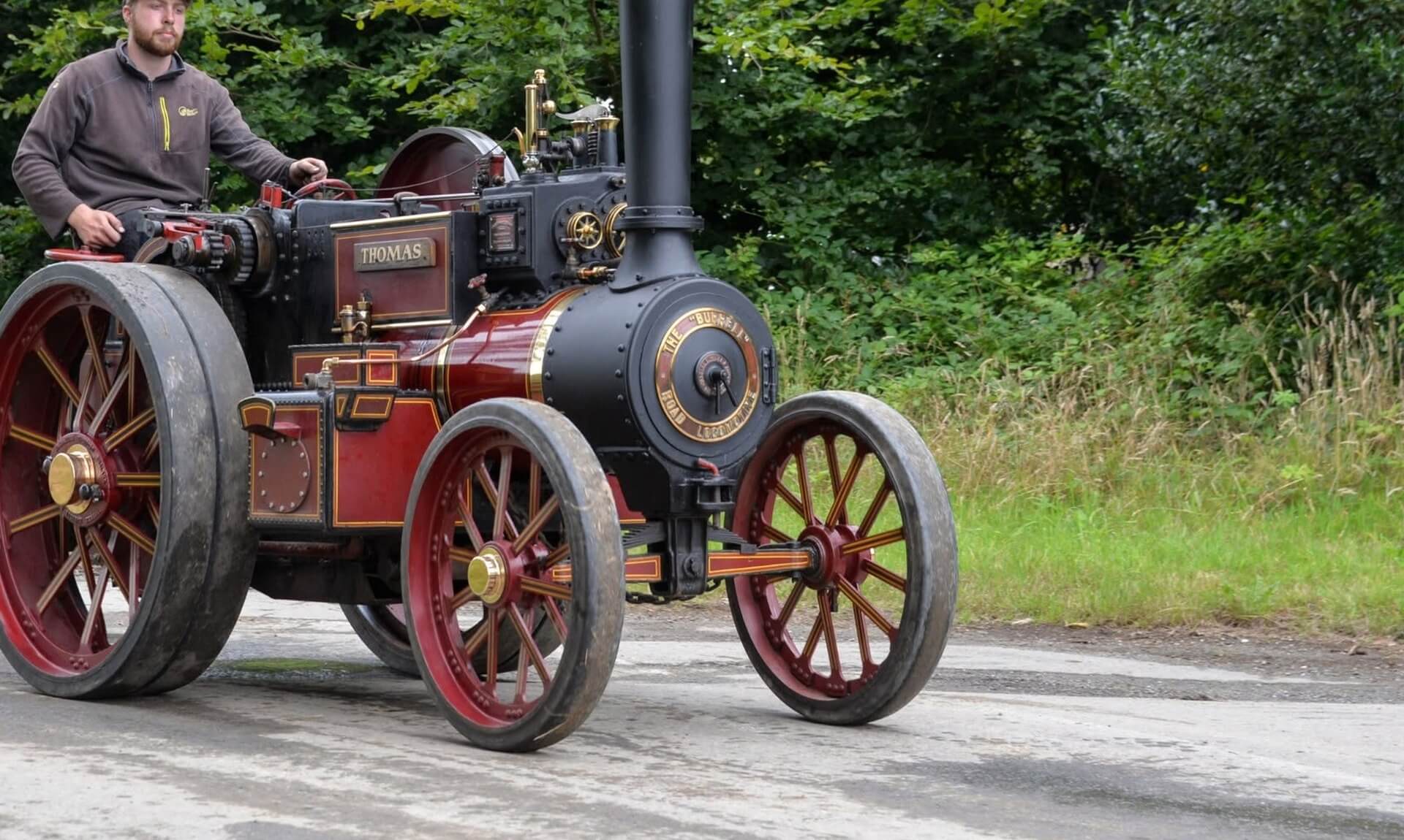Miniature Burrell steam road locomotive driven along a lane, the kind of engine on show at Boconnoc Steam Fair