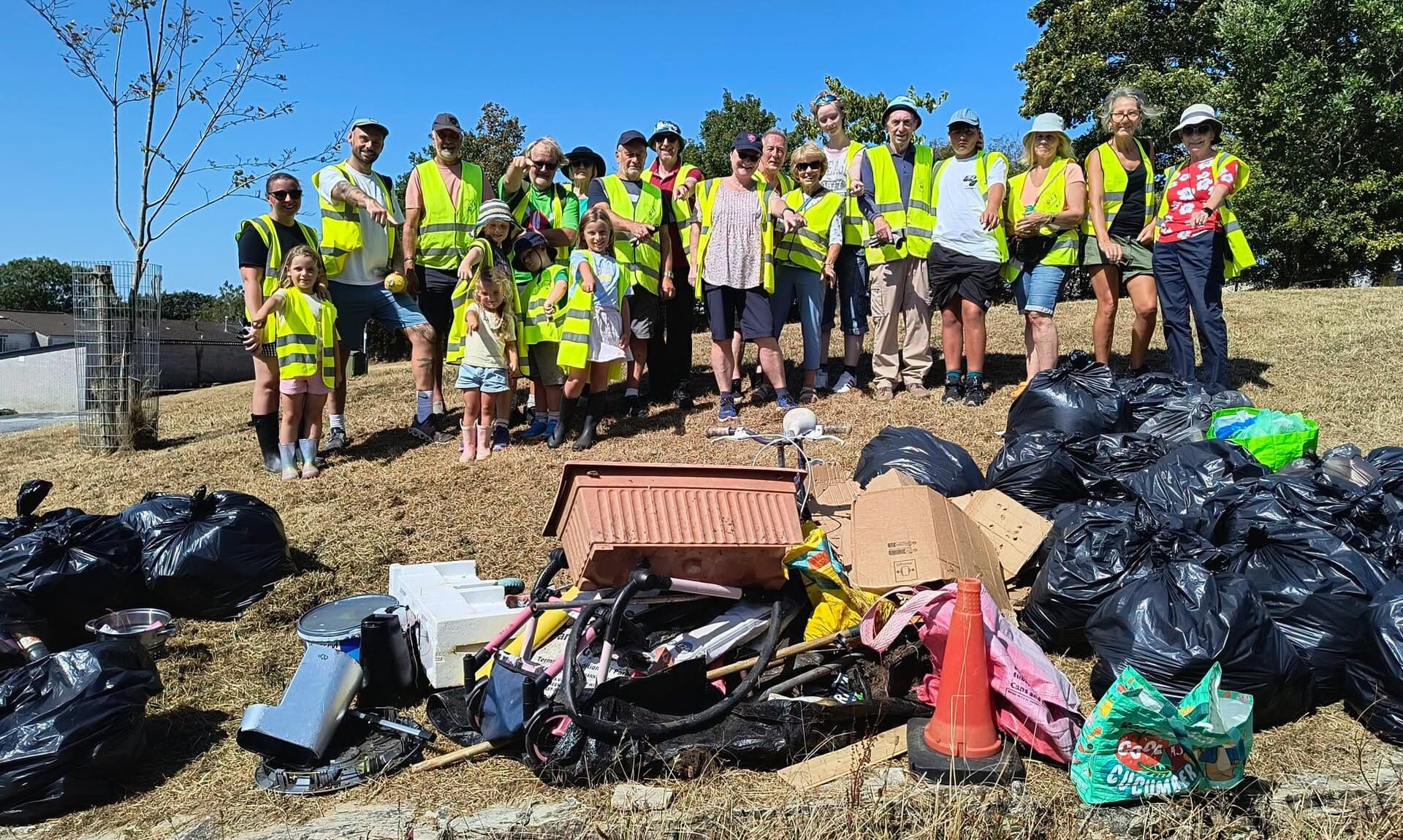 Volunteers in hi-vis vests stand behind bin bags and a pile of junk after a Bodmin litter pick