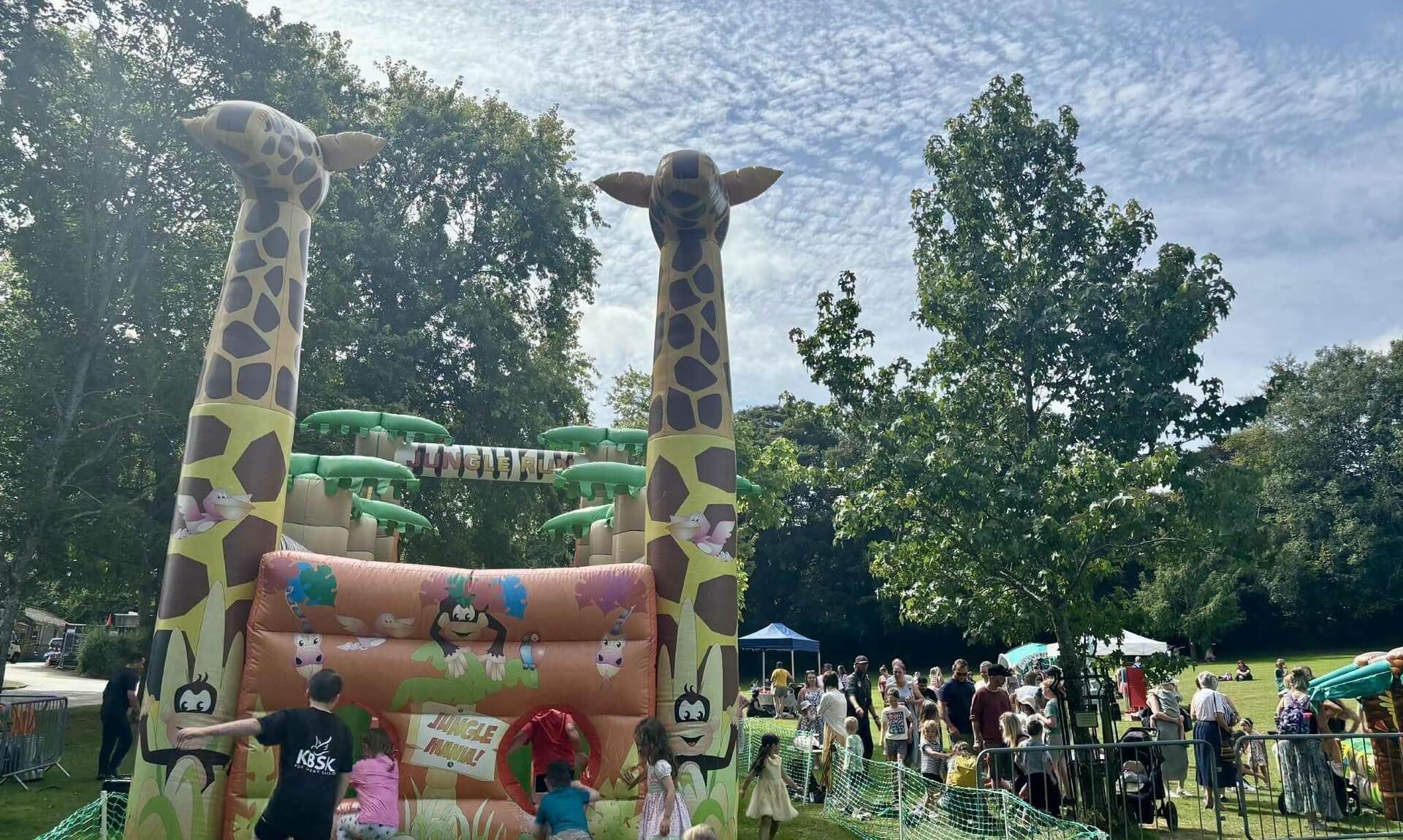 Giraffe-themed Jungle Run inflatable and families at an event in Priory Park, Bodmin